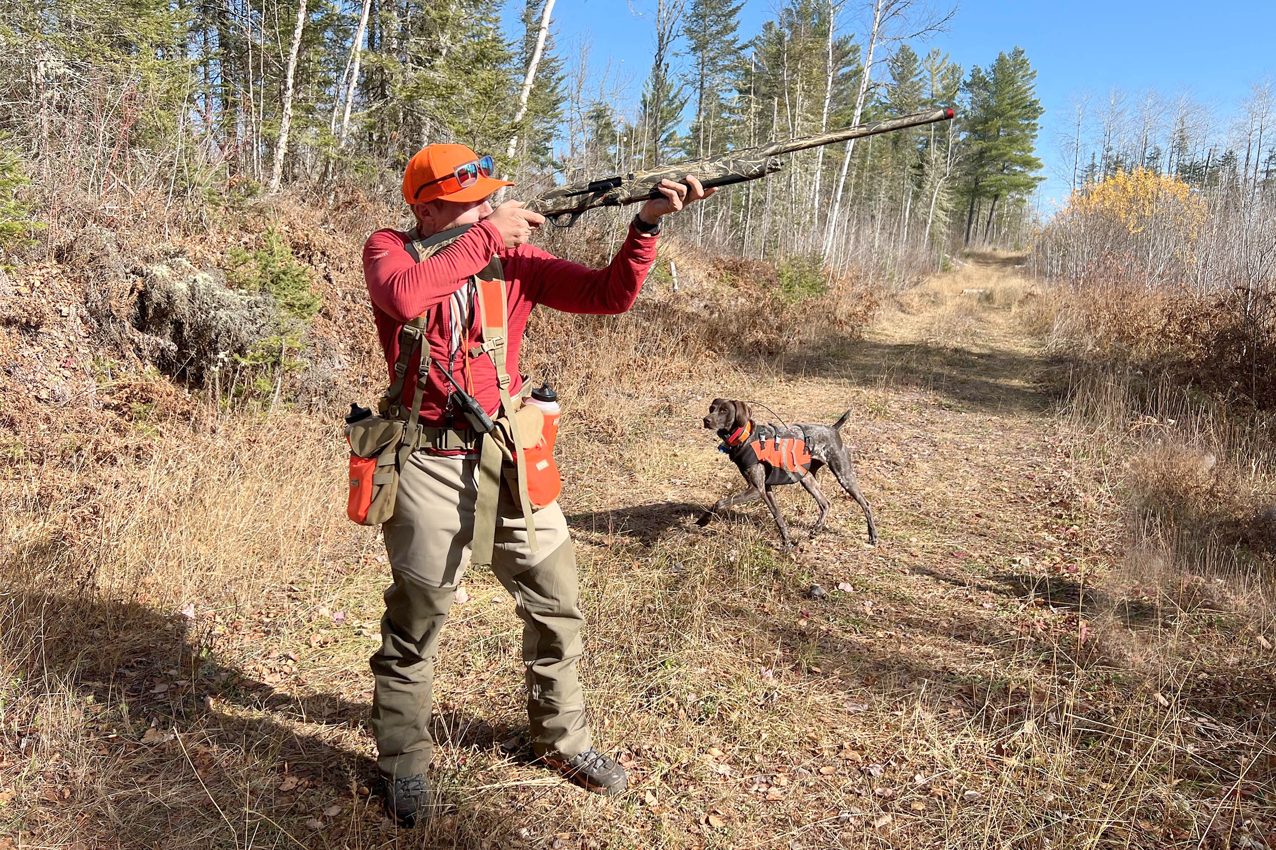 Hunter shooting ATA NEOX 12-Gauge Shotgun on logging trail with a dog
