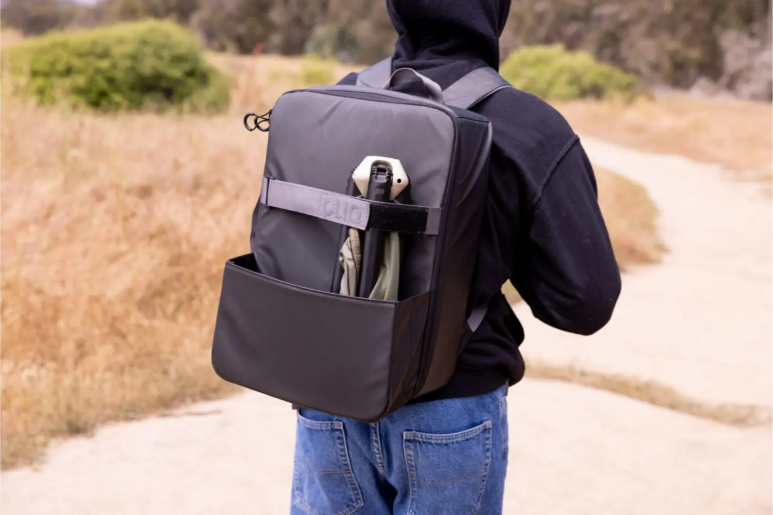 View of a person wearing a hoodie with a black bag walking down a trail