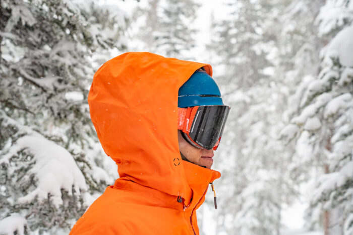 man has snow jacket hood pulled over helmet and the fit is not ideal