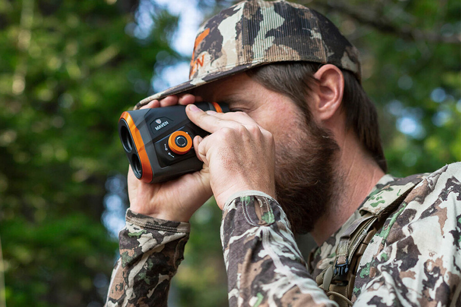 Person holding the Maven Rf.1 Rangefinder while hunting with a camo hat and shirt..