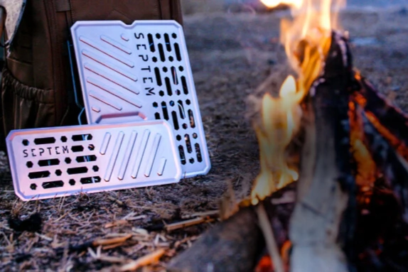 Two lightweight metal grills outside near a campfire.