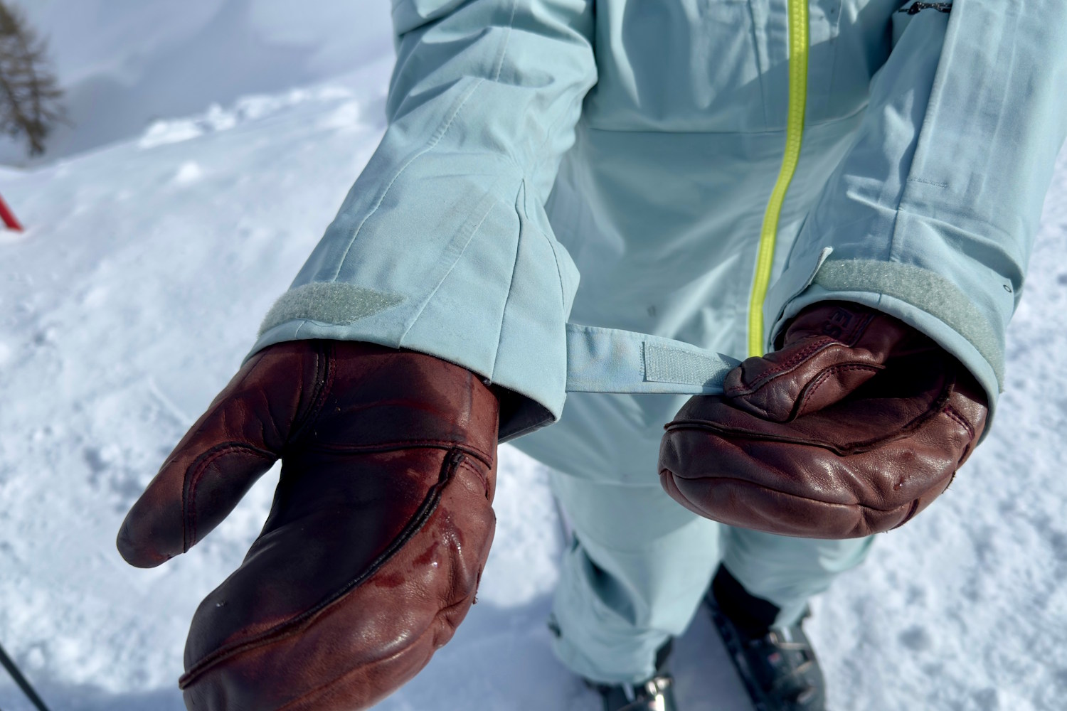 Close-up of a person adjusting the wrist cuff of Columbia ski jacket while wearing brown leather mittens
