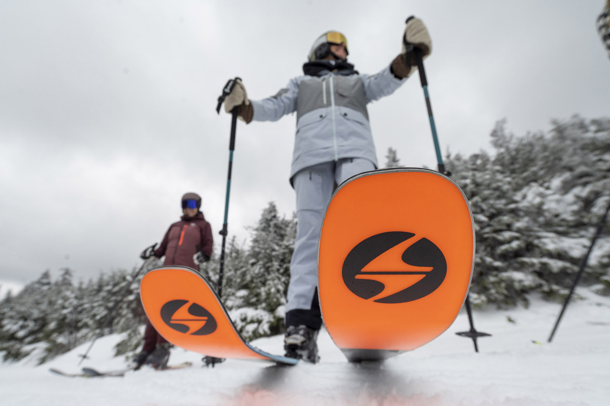 Close-up of the Blizzard Black Pearl 88 ski tips in the snow with skiers standing behind