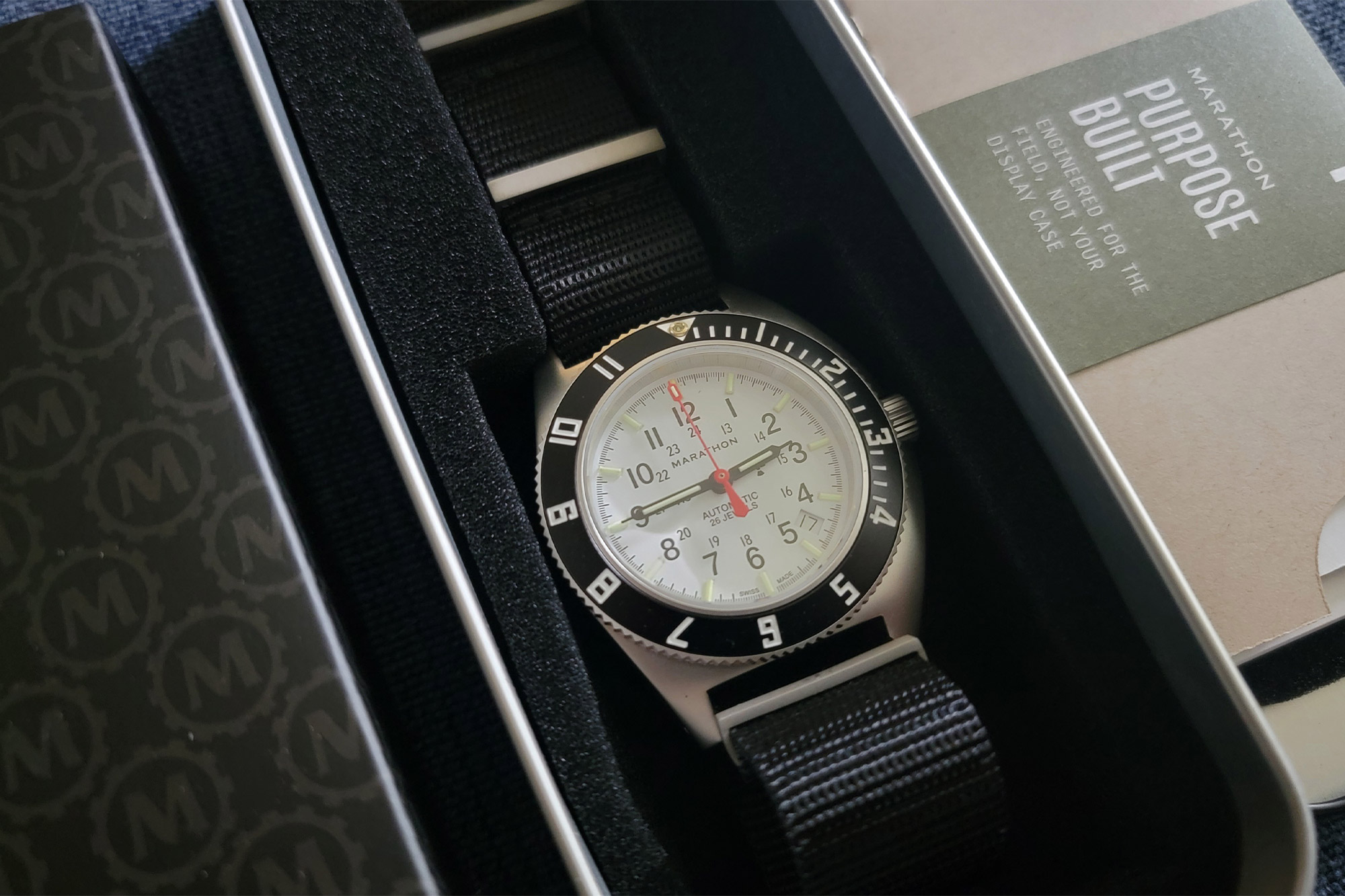 The Marathon SSNAV-D Auto Arctic Edition in its metal case with the “Purpose Built” tag visible beside it