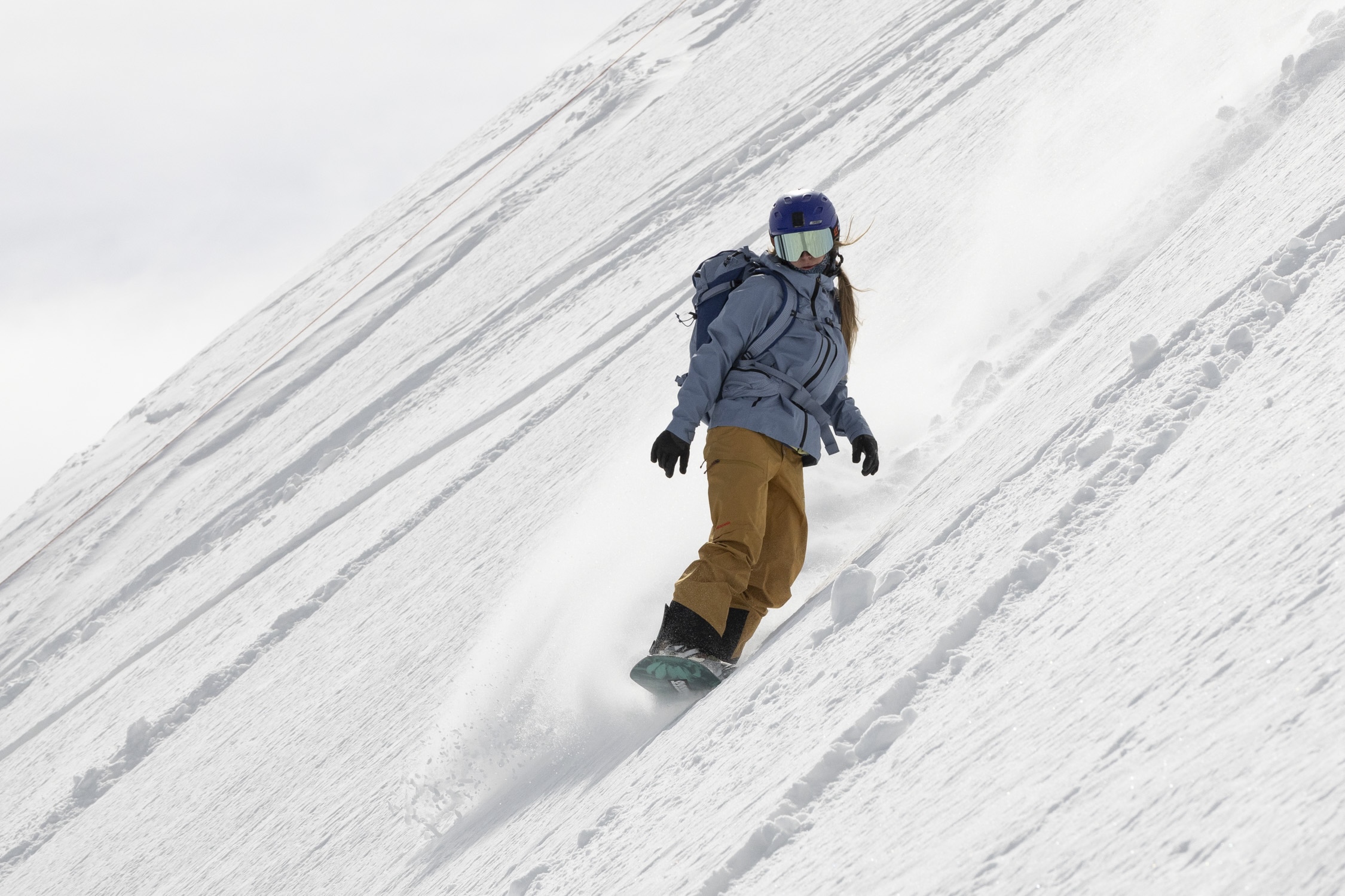 Snowboarder on steep slope in Patagonia PowSlayer shell