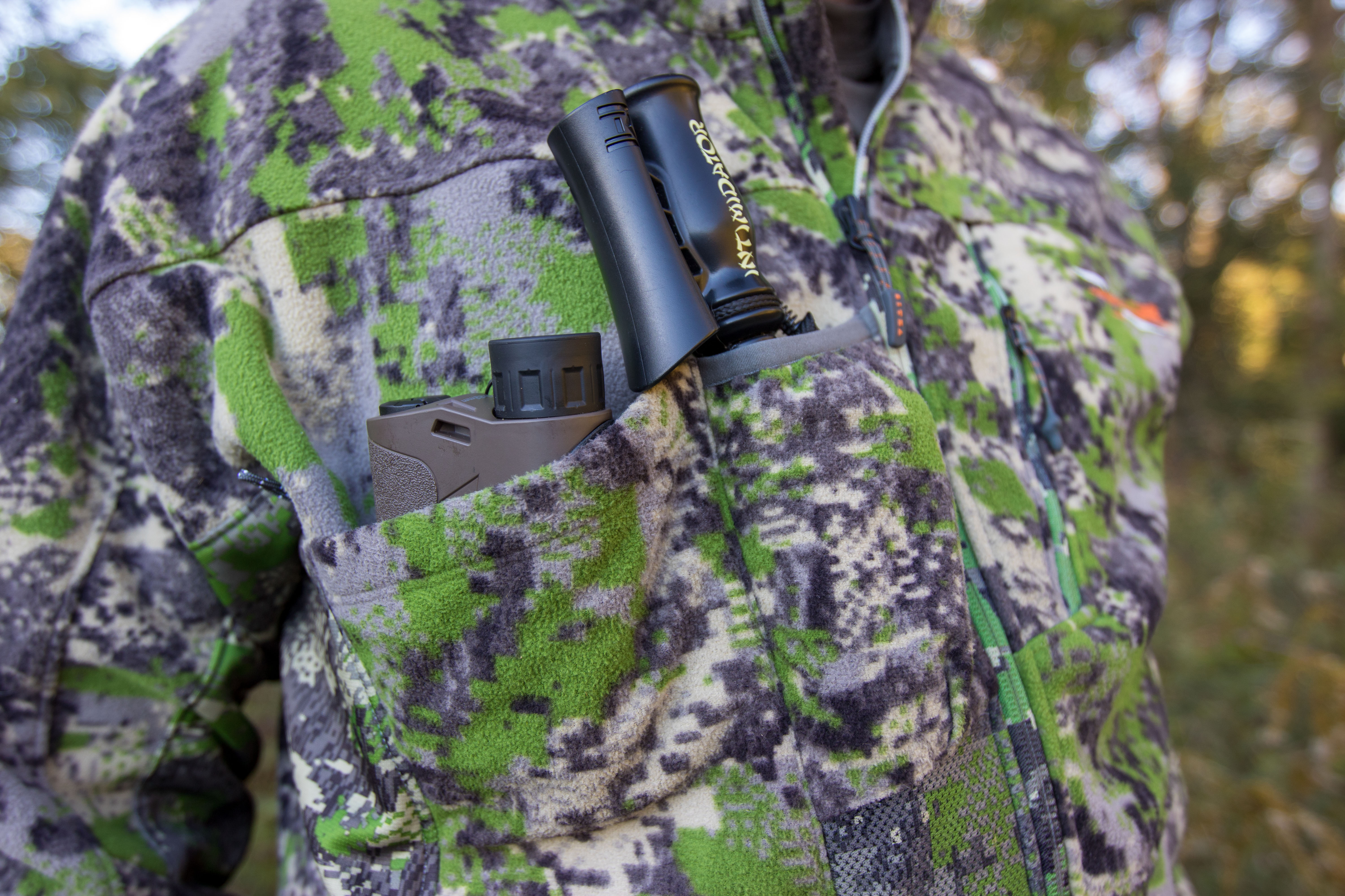 A deer call and a rangefinder in a hunting jacket pocket