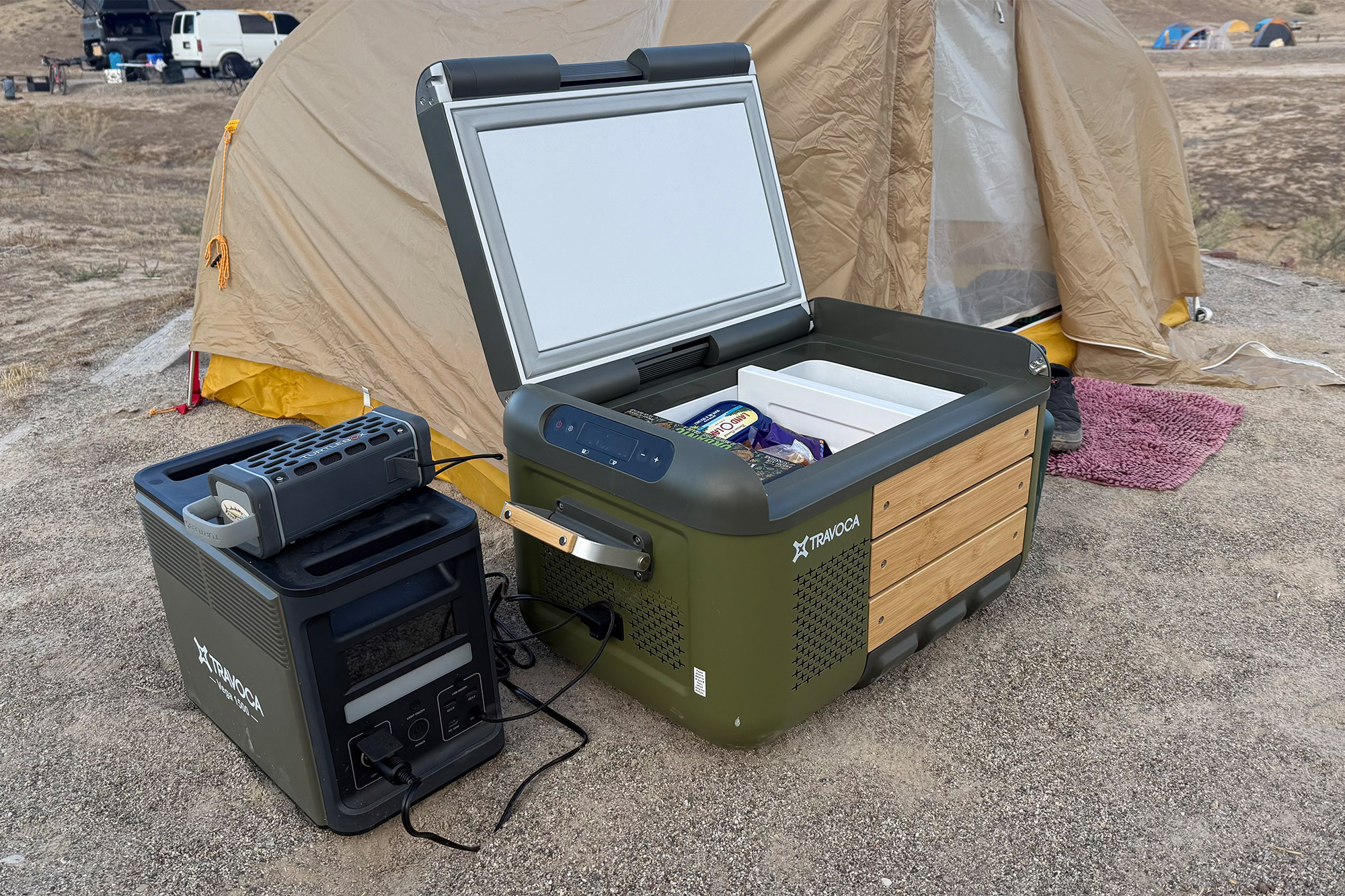 The TRAVOCA Rigel DZ eCooler and Vega 1500 power station set up beside a camping tent