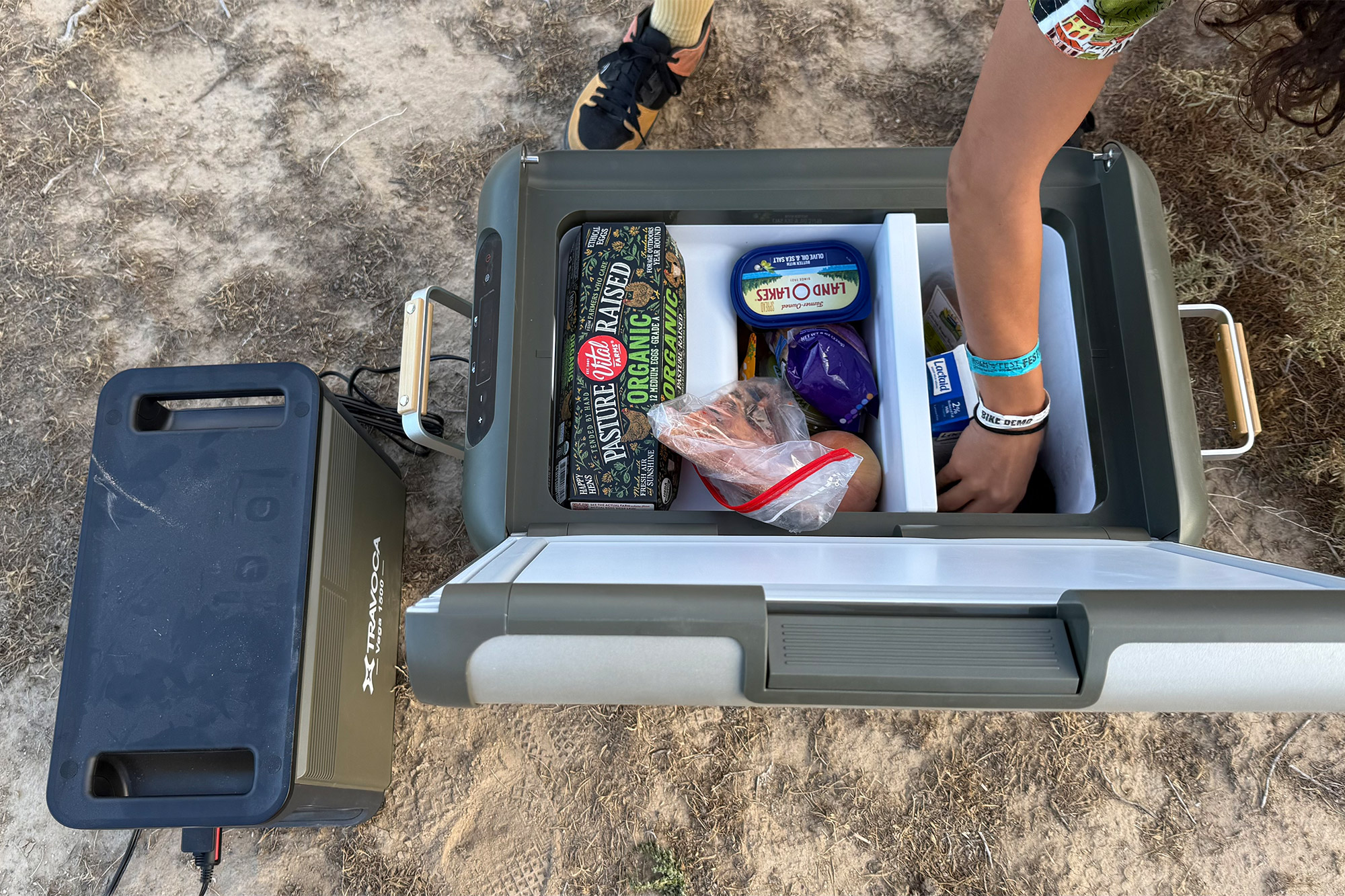 A person reaches into the TRAVOCA Rigel DZ eCooler to grab food while it’s powered at camp