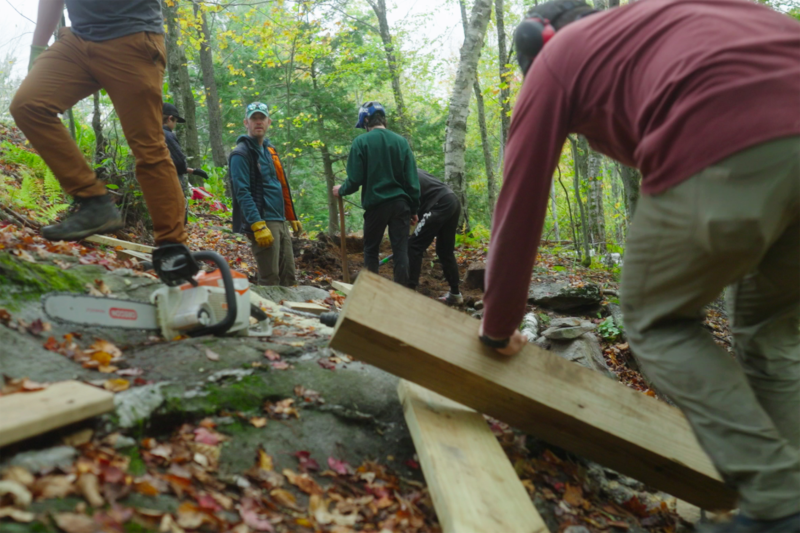 People with tools and lumber work on building a trail