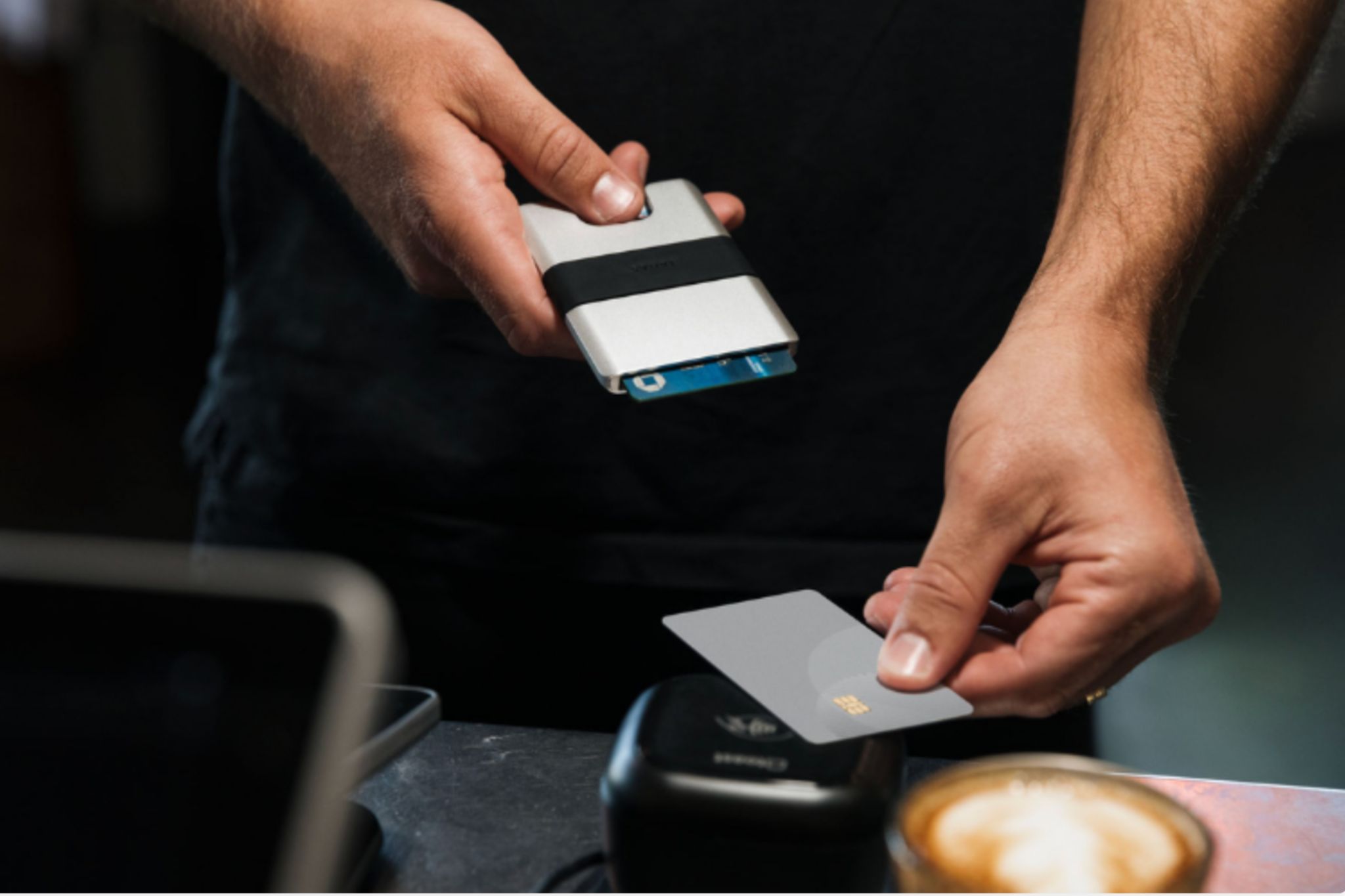 Close up shot of person with wallet tapping to pay for a coffee