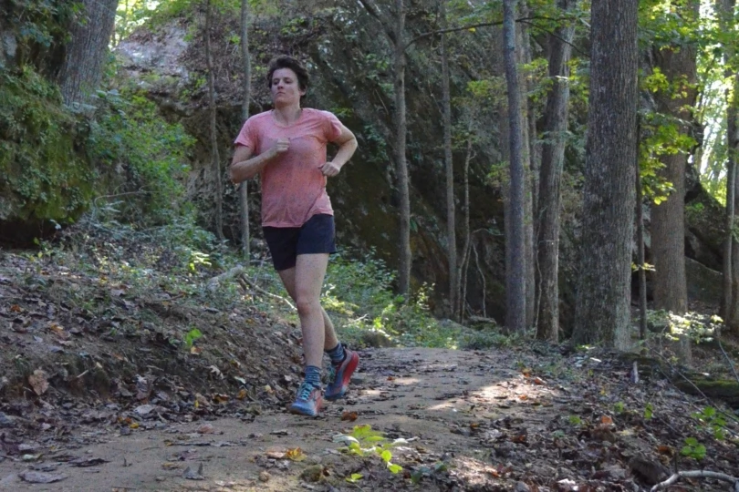 Person runs on trail in woods 