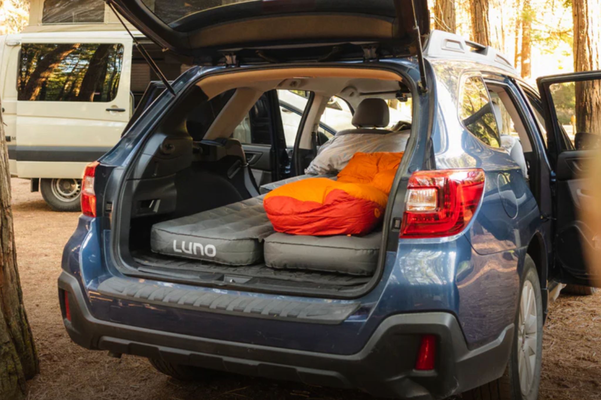 view of car with mattresses set up for camping from back with hatchback open