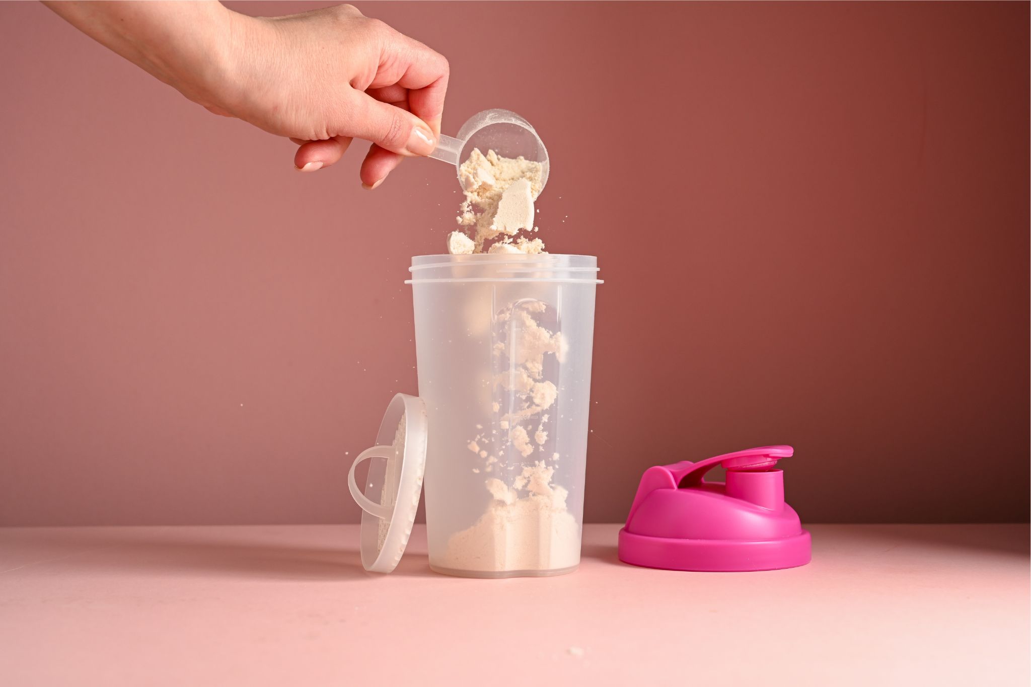 person pouring protein powder into shaker bottle