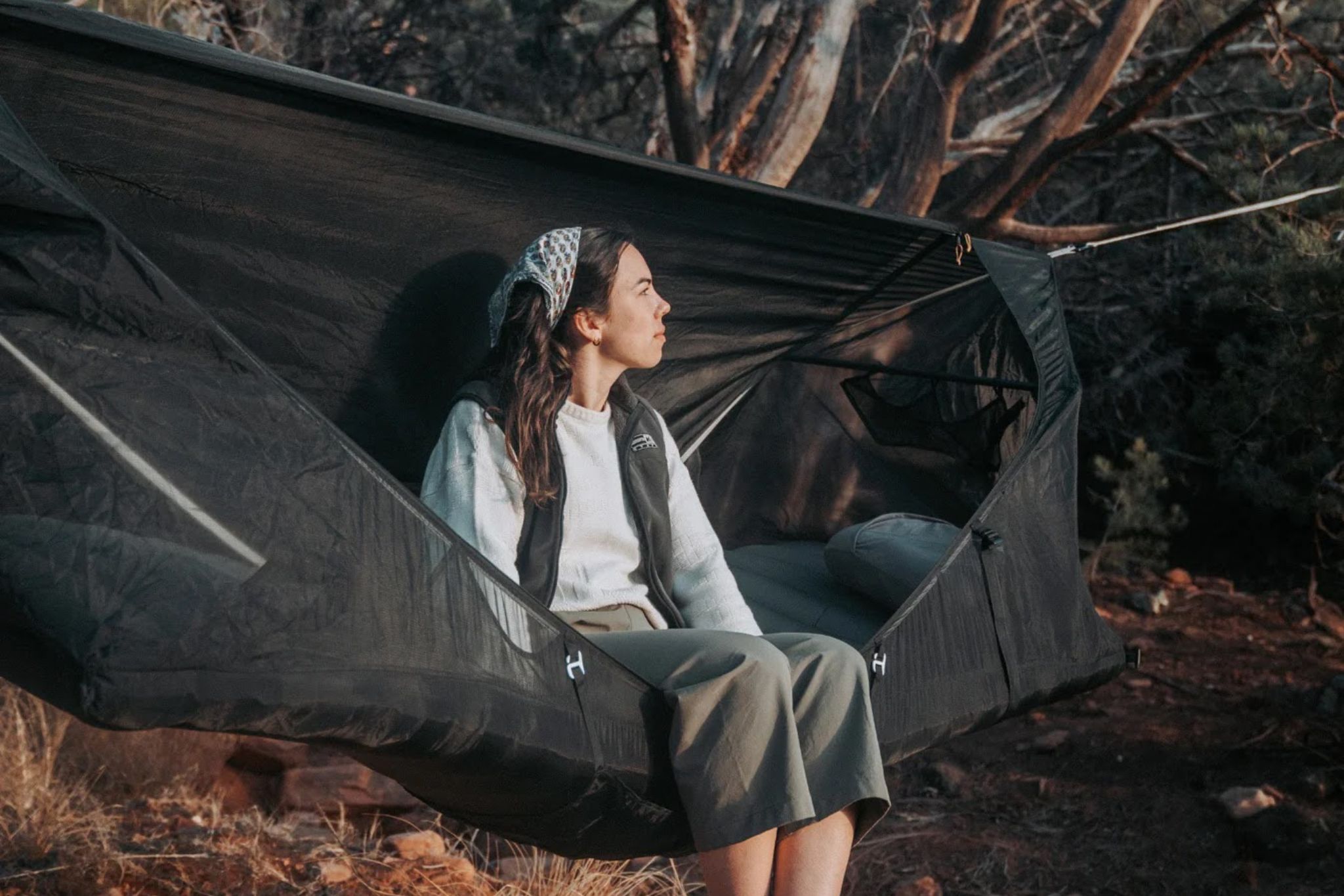 Woman sits in hammock set up outside