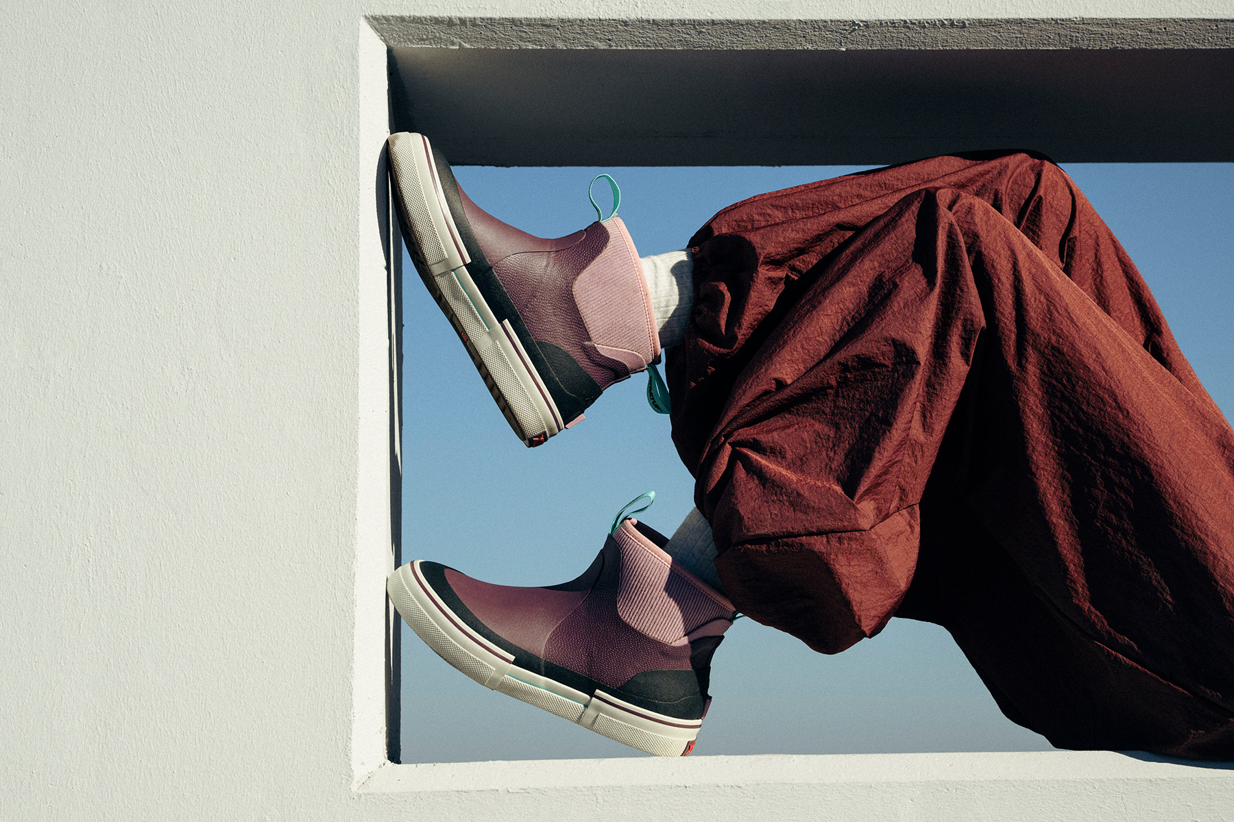 Close up shot of person sitting on ledge wearing rain boots