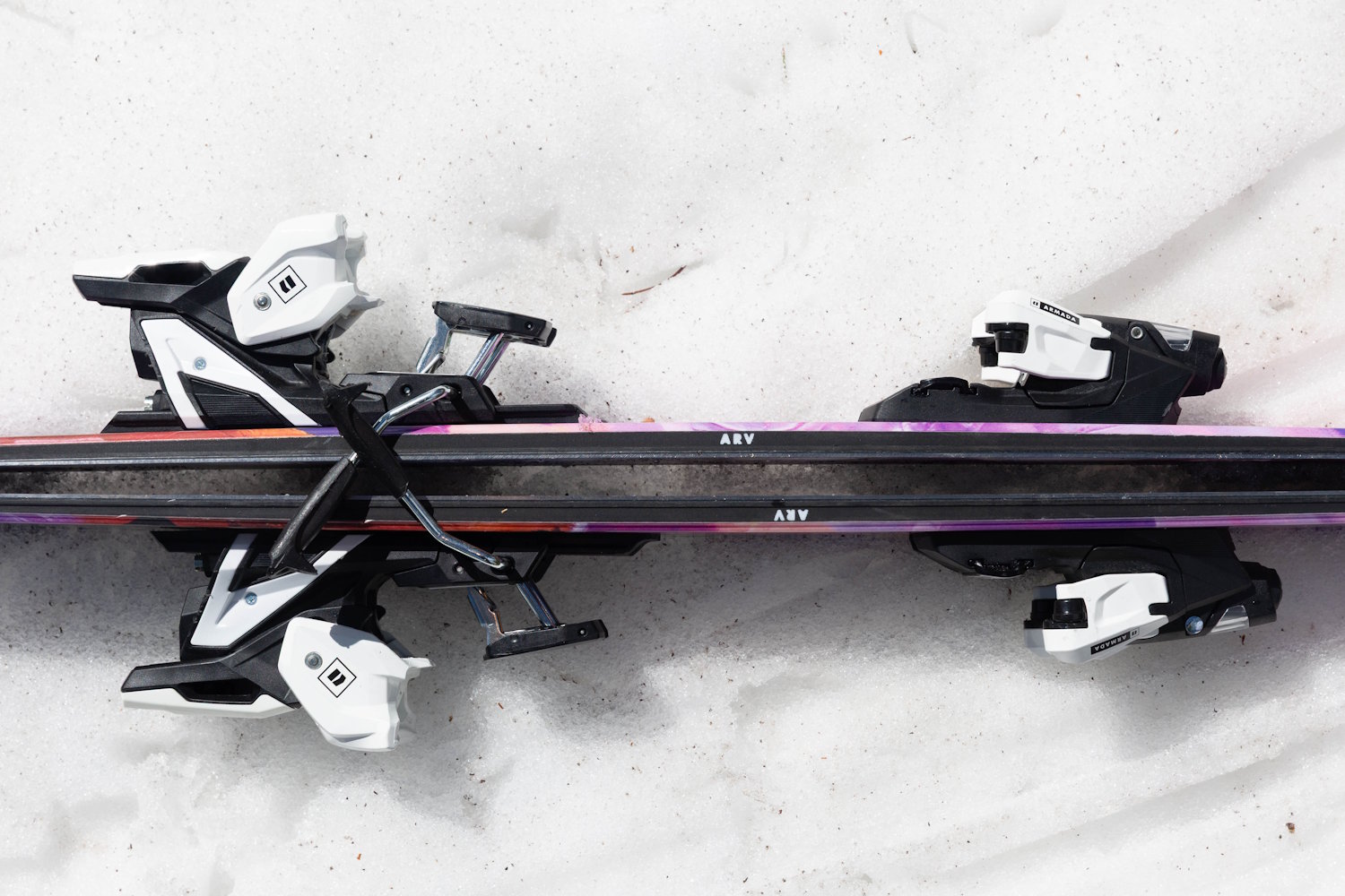 Close-up view of two pairs of Armada ARV 100 skis with white and black bindings, resting base-to-base on snow.