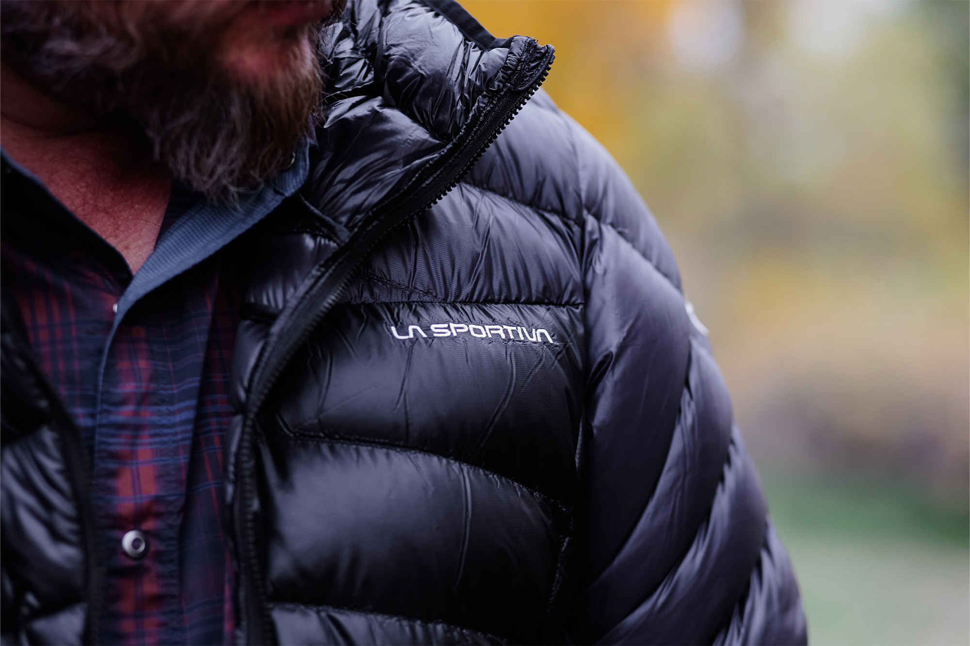 Close-up of the La Sportiva logo stitched on the chest of the shiny black jacket