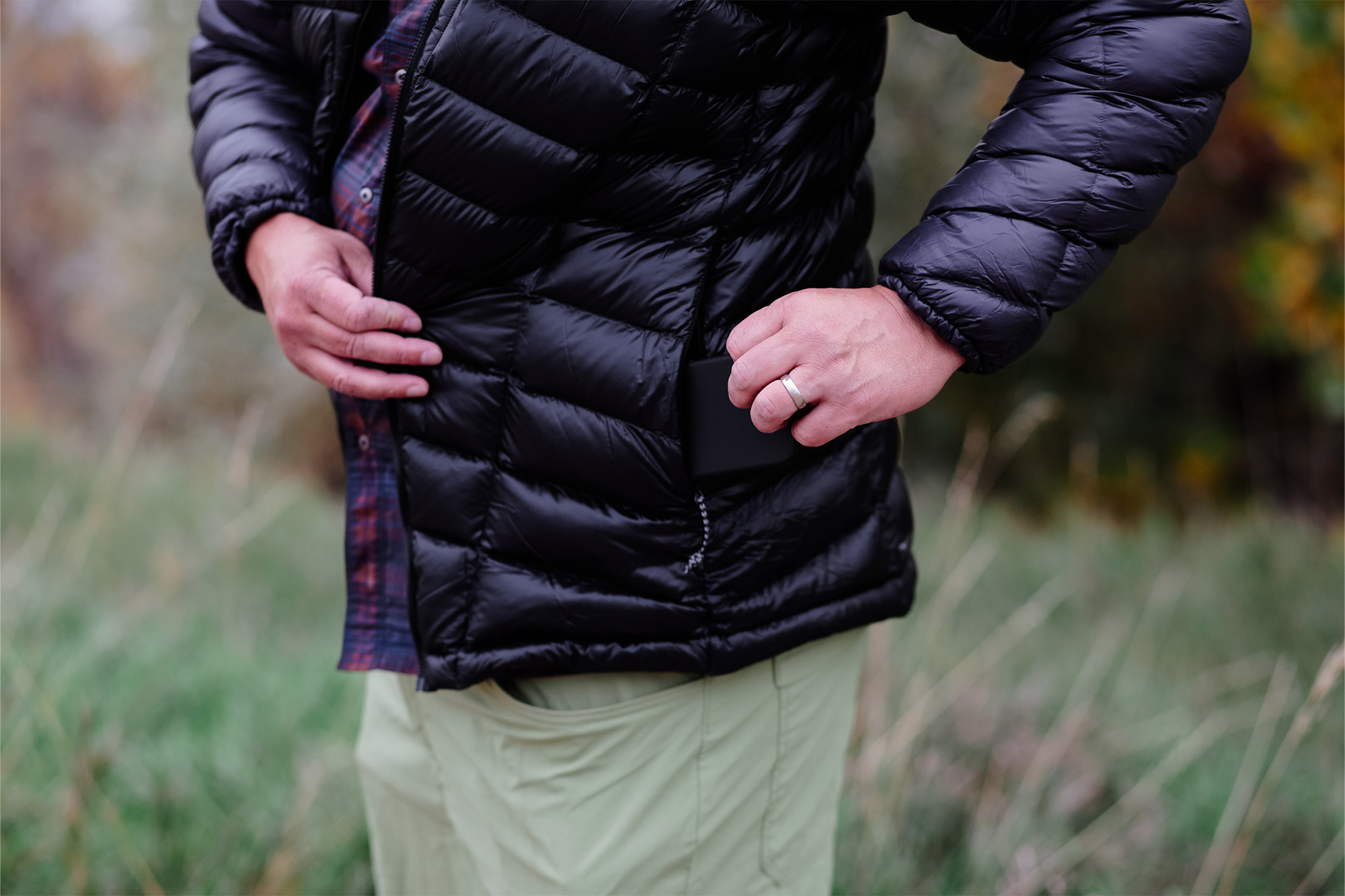A man’s hand slips an item into the side pocket of the black puffer jacket