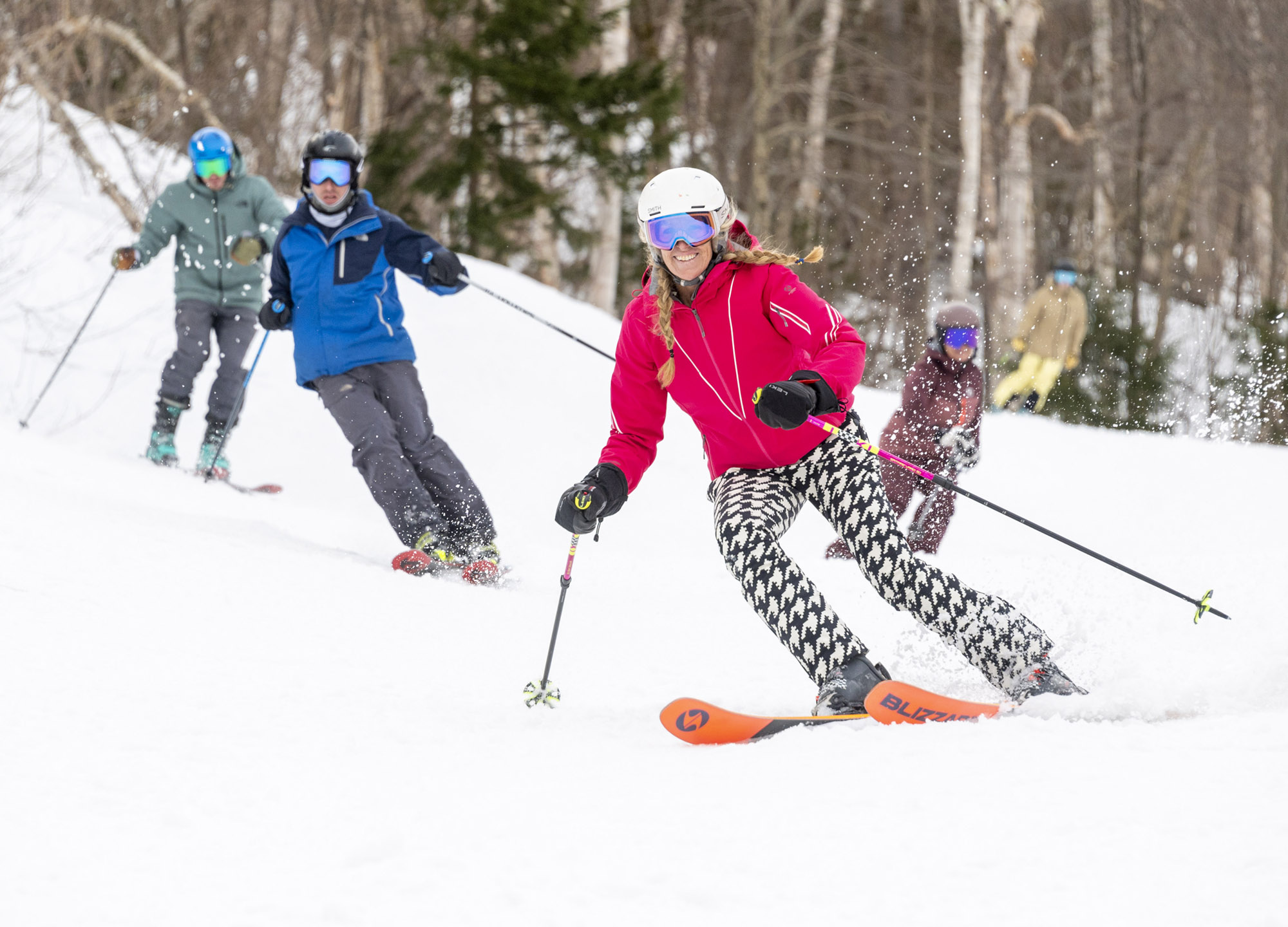 A group skiing down the slope, lead skier wearing Blizzard Black Pearl 88 skis