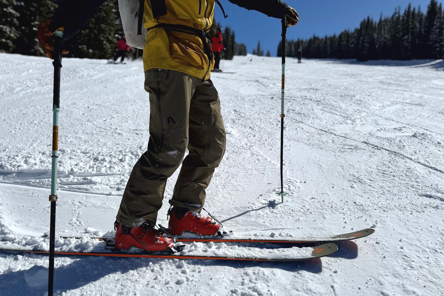 Person on skis in snow, wearing Flylow pants and holding trekking poles.