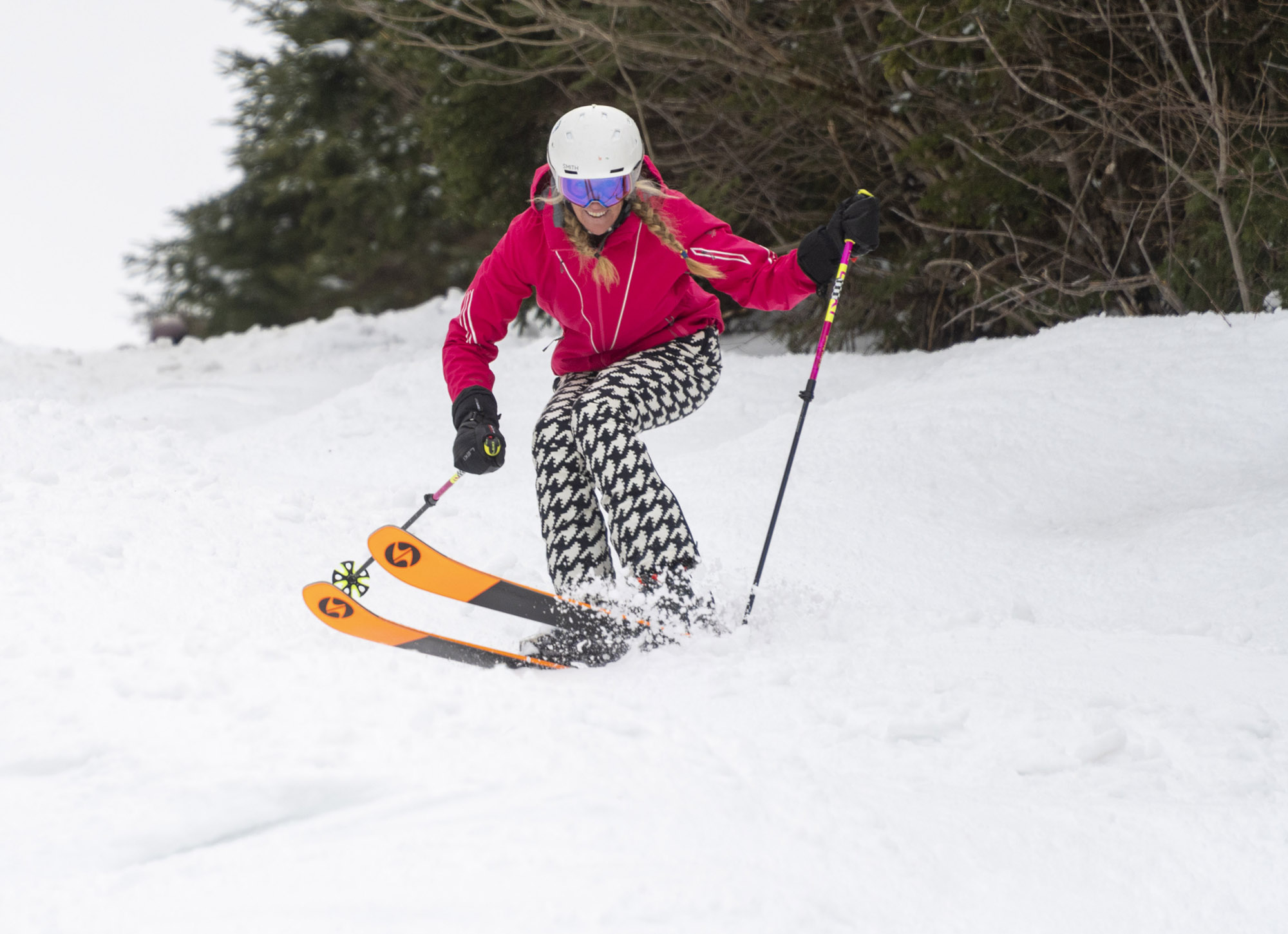 A skier in pink jacket and patterned pants skiing with Blizzard Black Pearl 88 skis