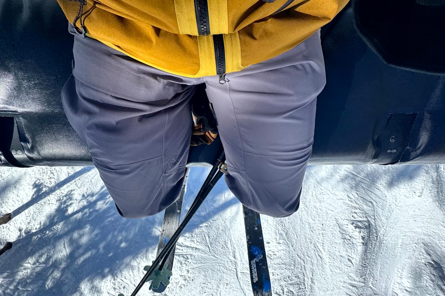 Person wearing gray Stio Environ pants sitting on a ski lift