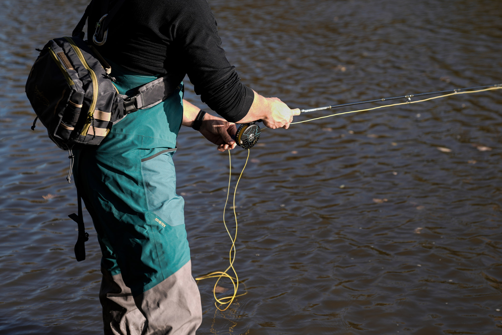 View of the angler’s waist and hands managing the yellow line while fishing