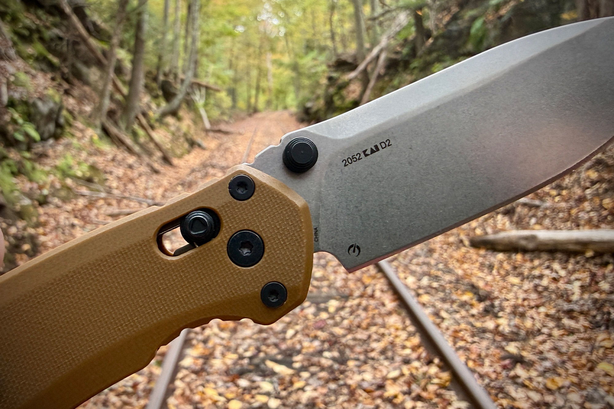 A close-up of the knife’s pivot and D2 steel marking taken on a forest trail