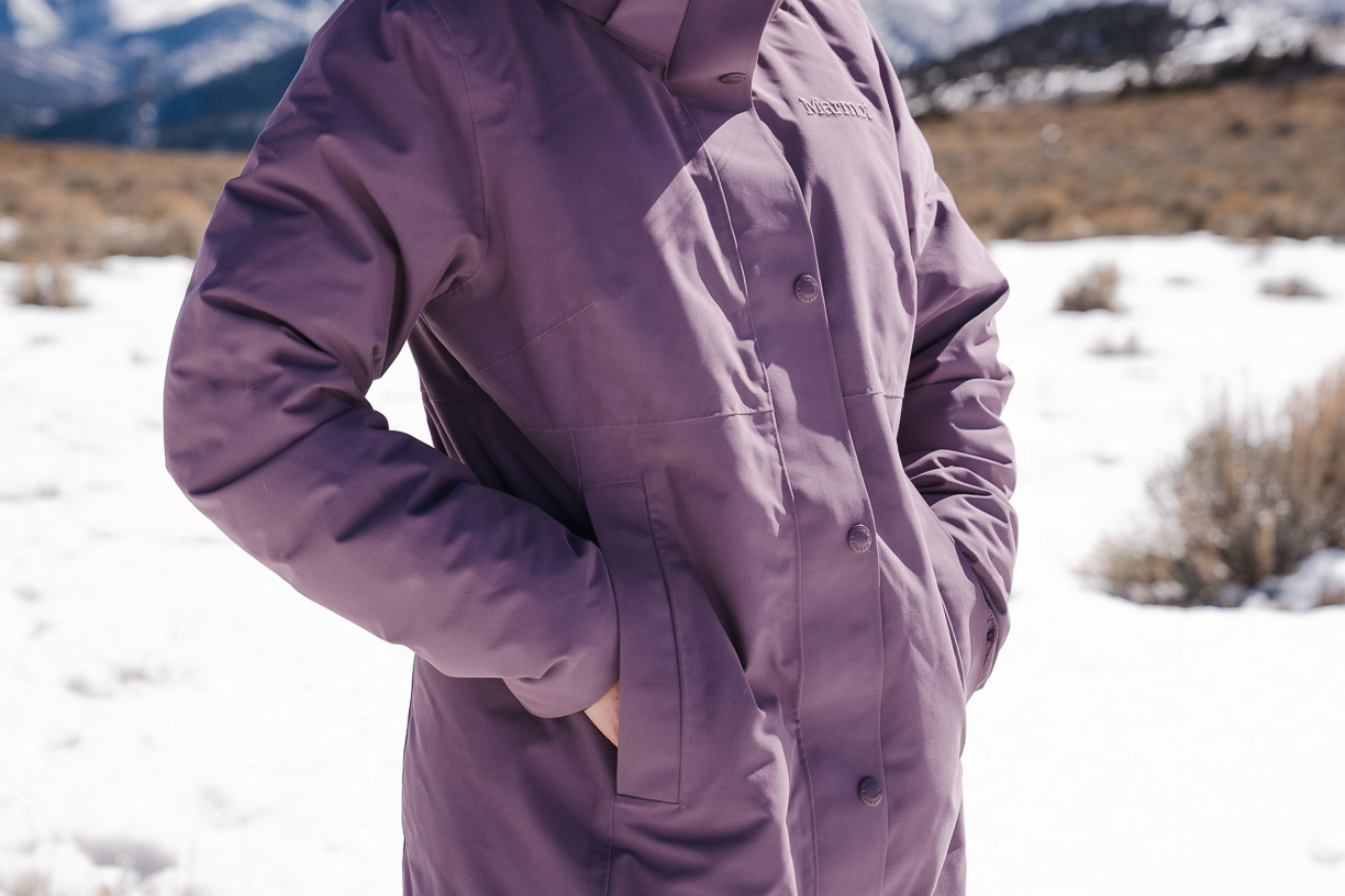 woman resting hands inside jacket packets of winter jacket 