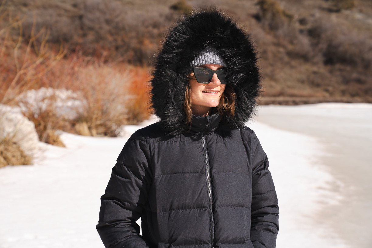 woman testing jacket with faux fur on hood