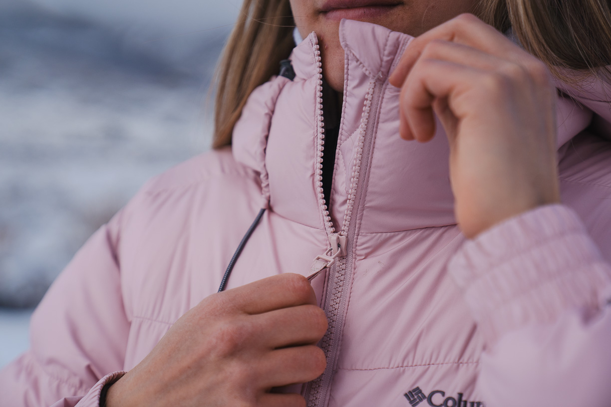 woman pulling a zipper pull down from the collar on a winter jacket