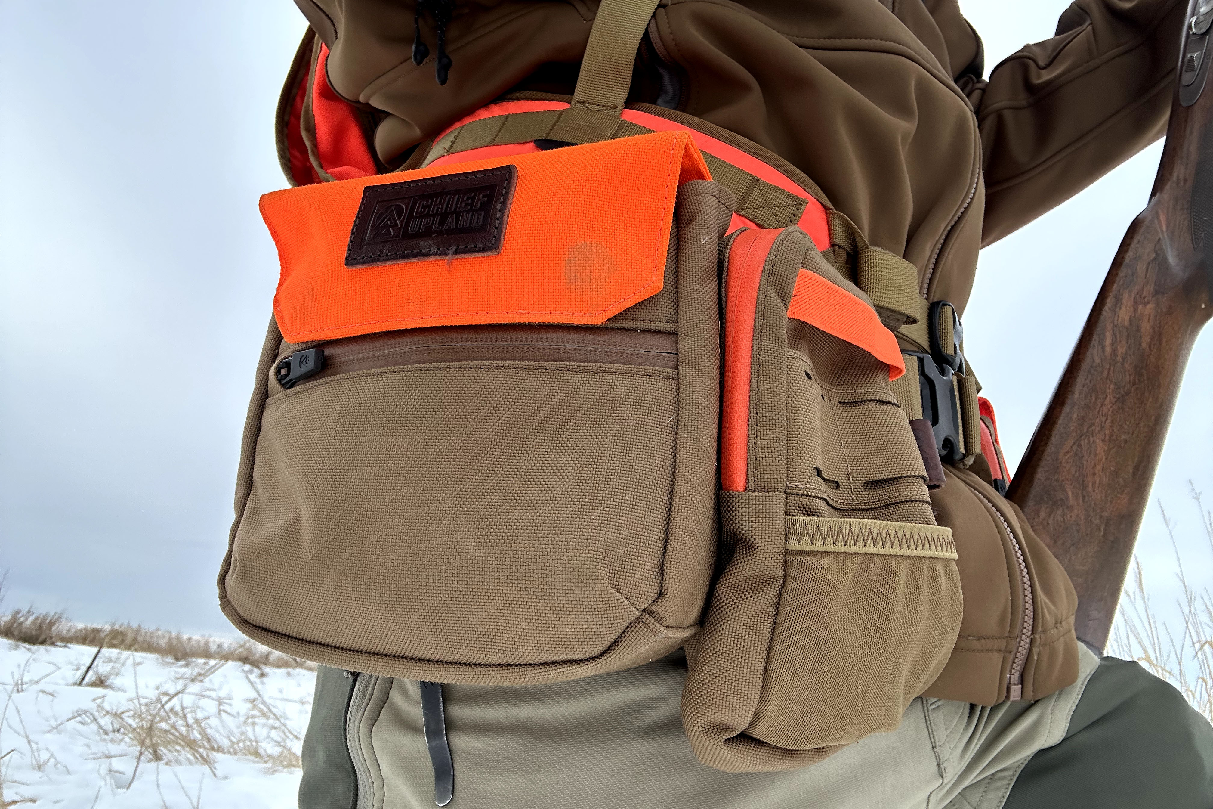 Pouches attached to the Chief Upland Over/Under Vest on a hunter who is leaning his shotgun against his leg.