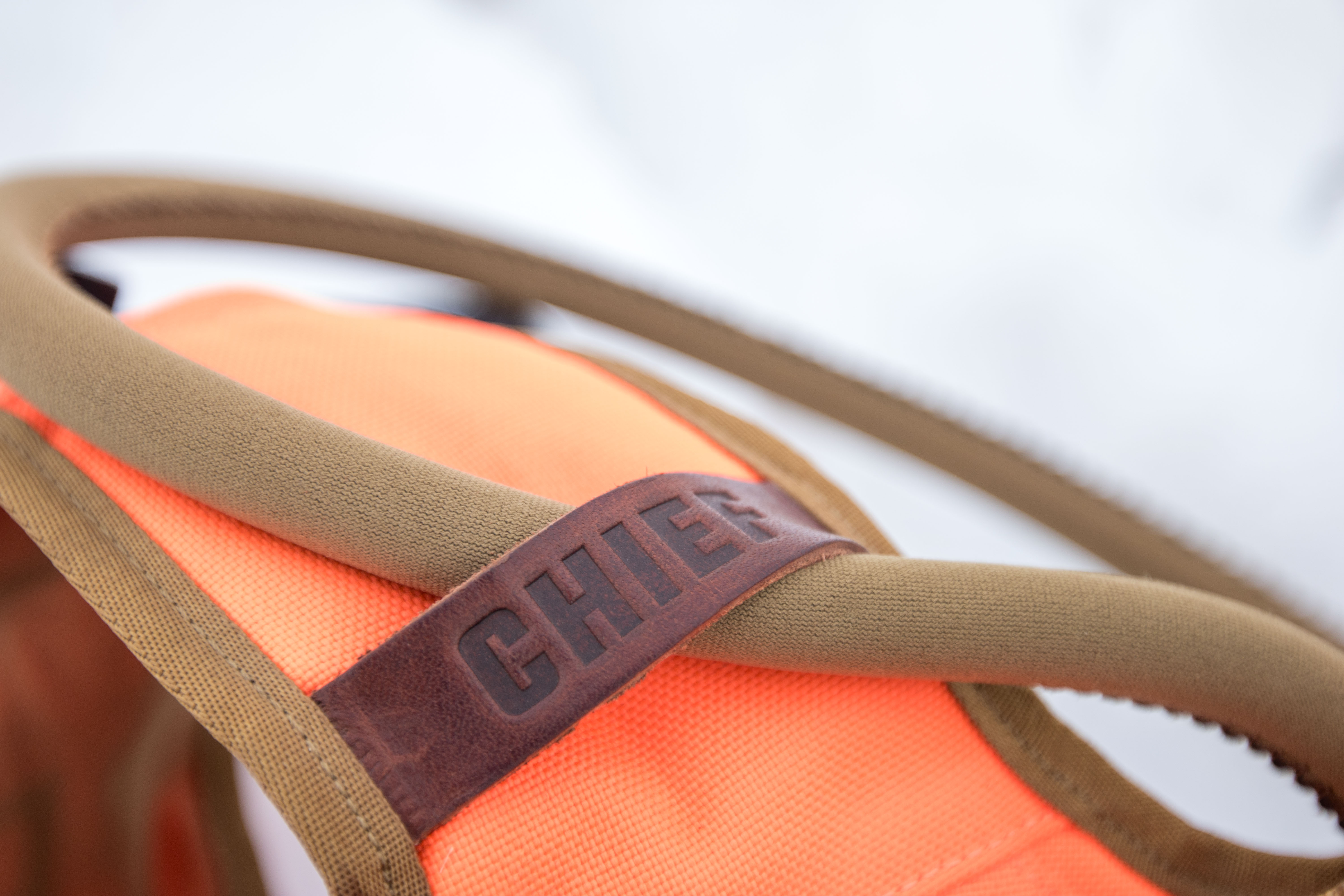 The tube of a camelback threaded through a leather strap on the Chief Upland Over/Under Vest.