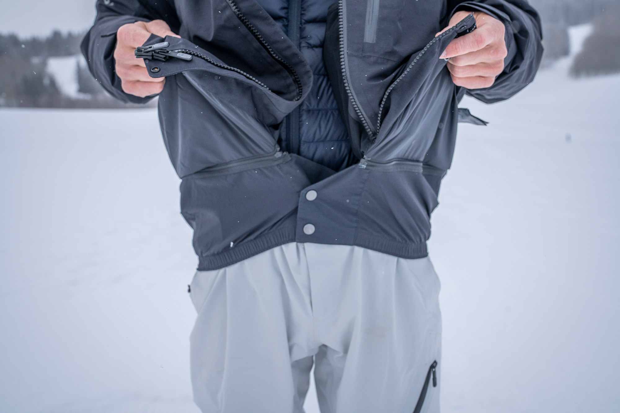The rider shows the Cyclic Jacket’s powder skirt open, revealing how it seals to keep snow out