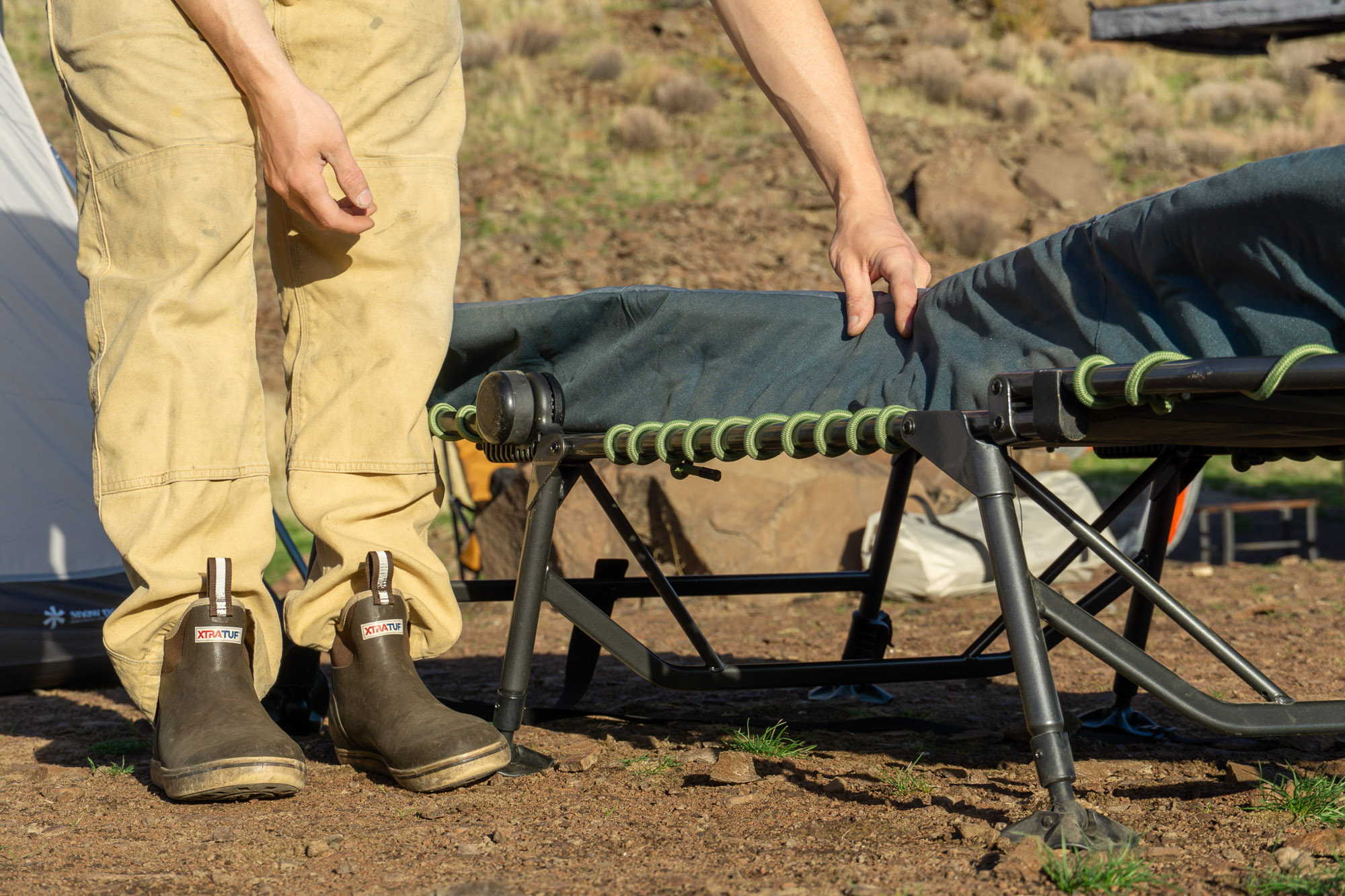 the author lifts the pad of the cot to show the suspension system