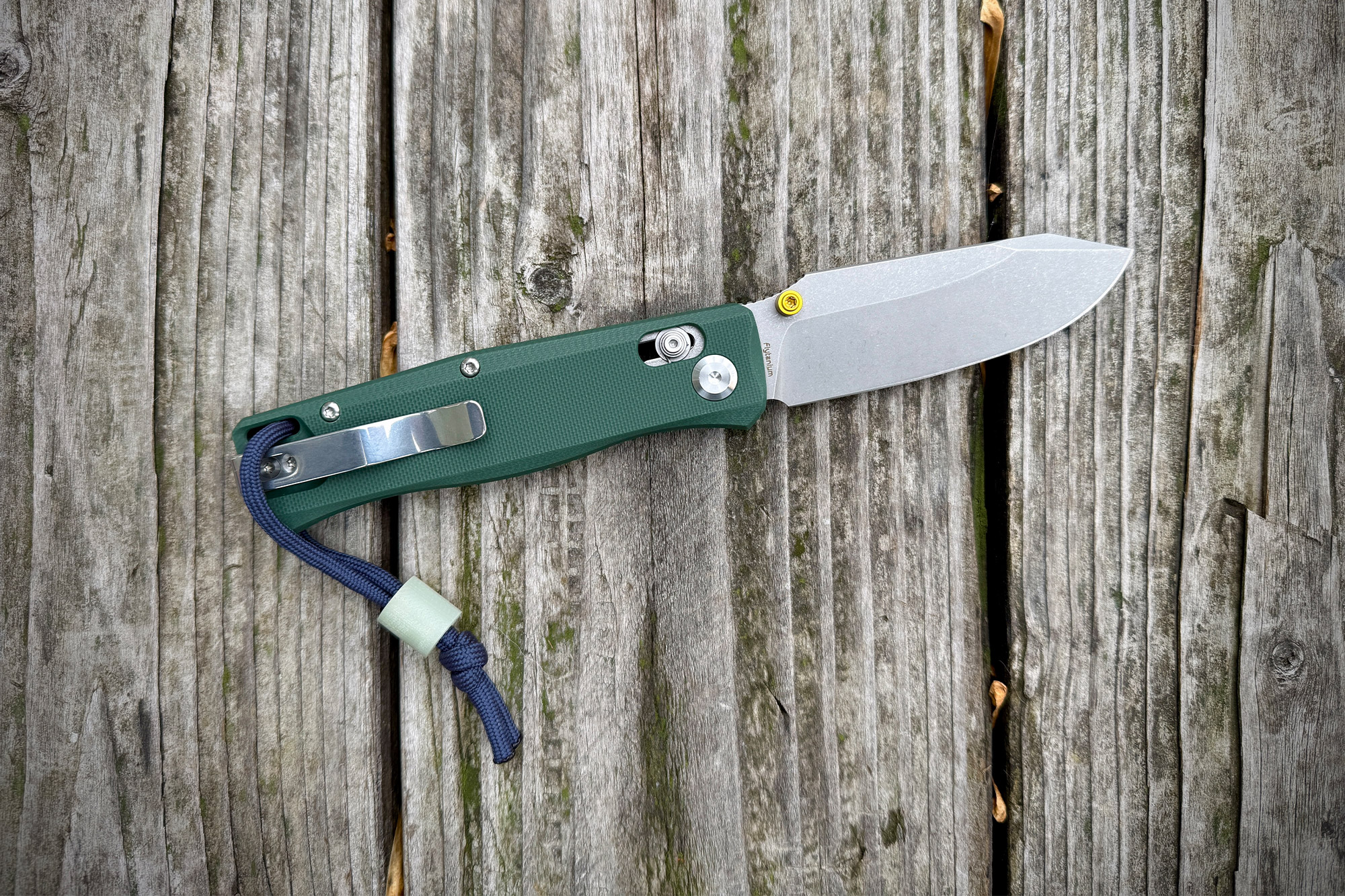 The BEEF knife fully opened on a weathered wooden board