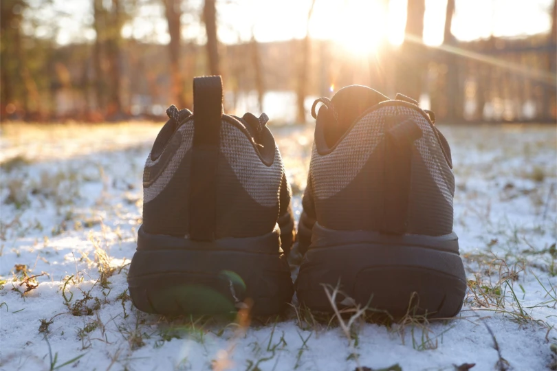 Rear view of two shoes sitting on snow with sunlight in the background