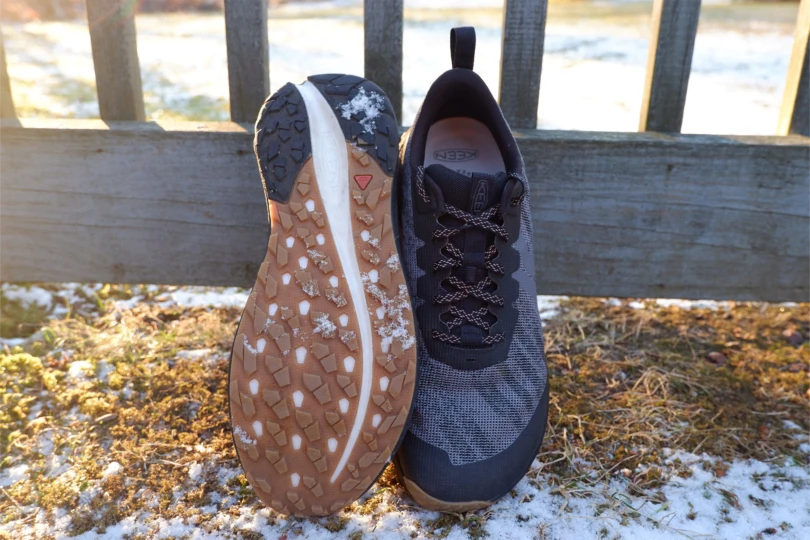 One shoe flipped to show the outsole next to another shoe on snowy ground