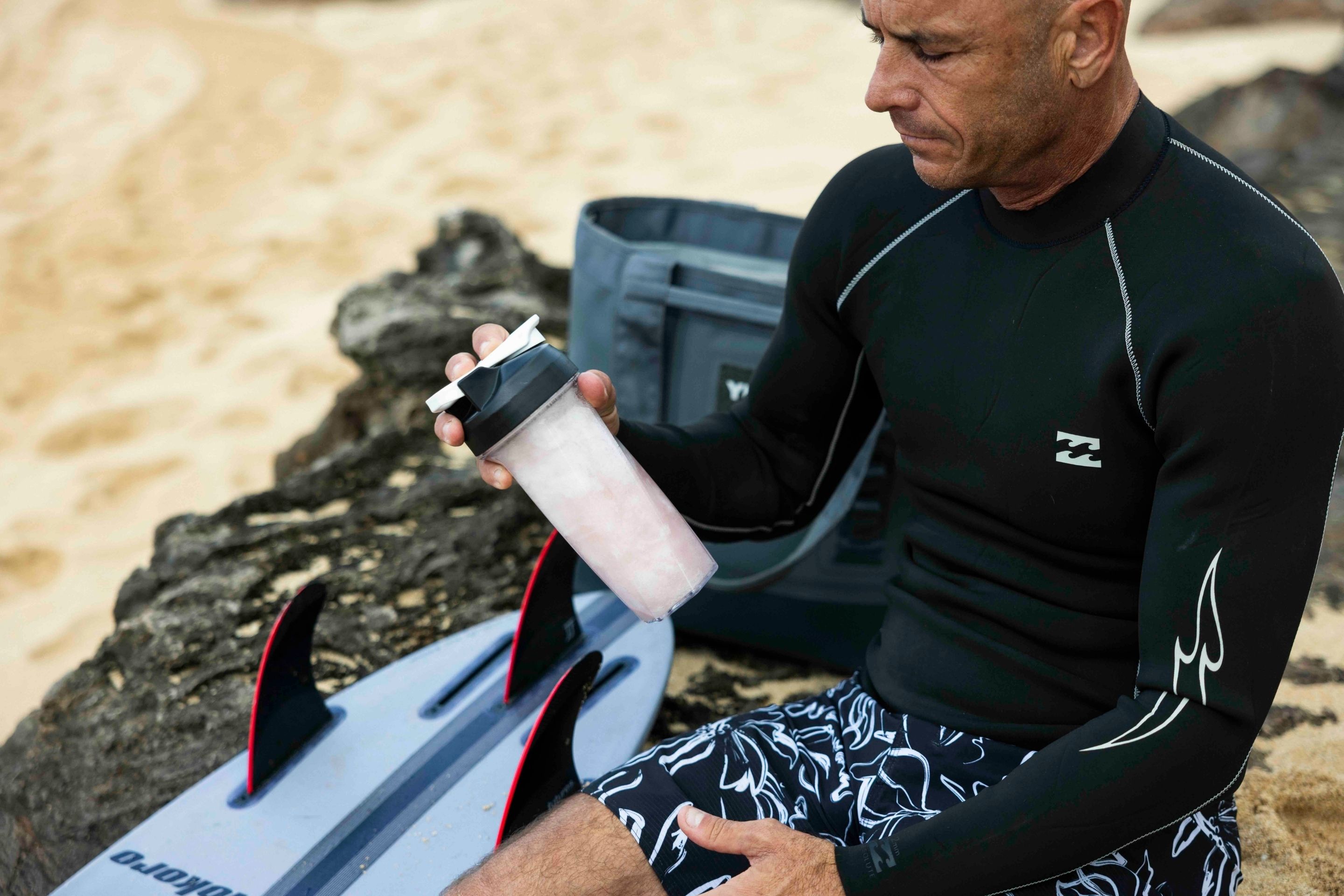 surfer on beach mixing shaker bottle