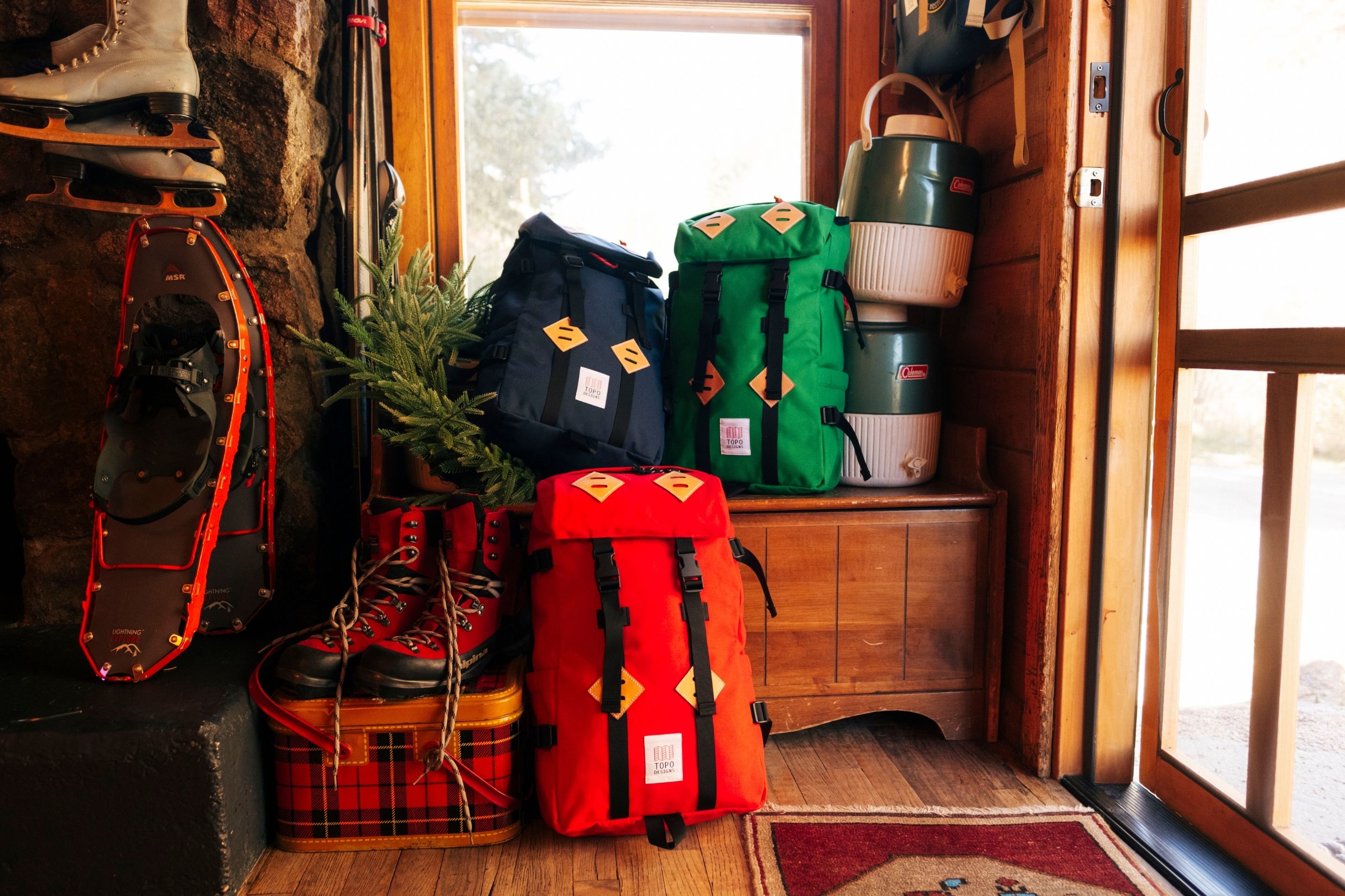 backpacks in three colors lined up in entryway