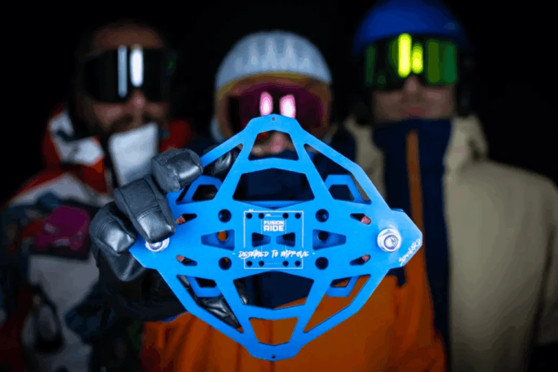 Circular blue snowboard suspension system in focus being held by three riders in background