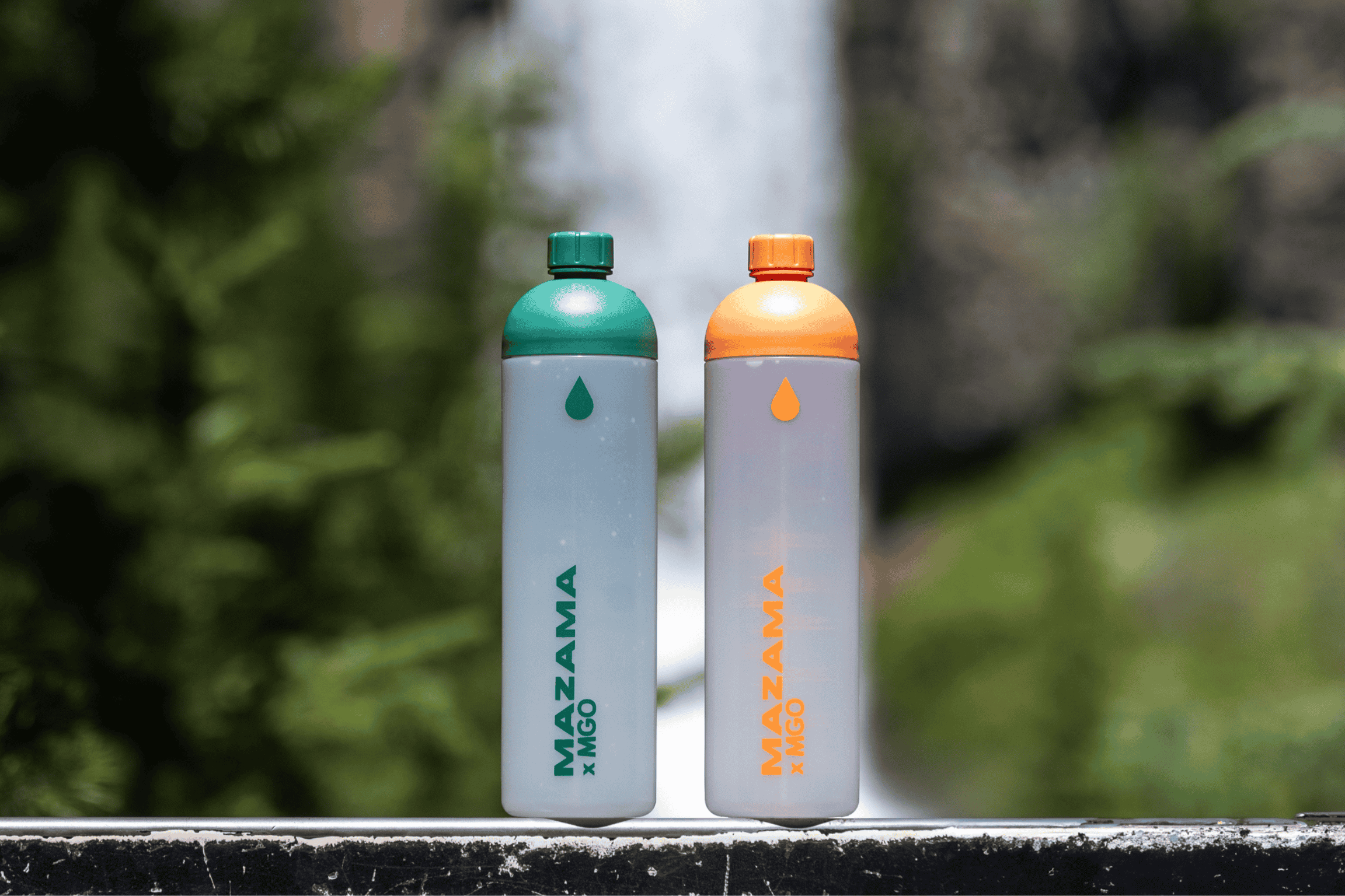 two water bottles in front of a waterfall