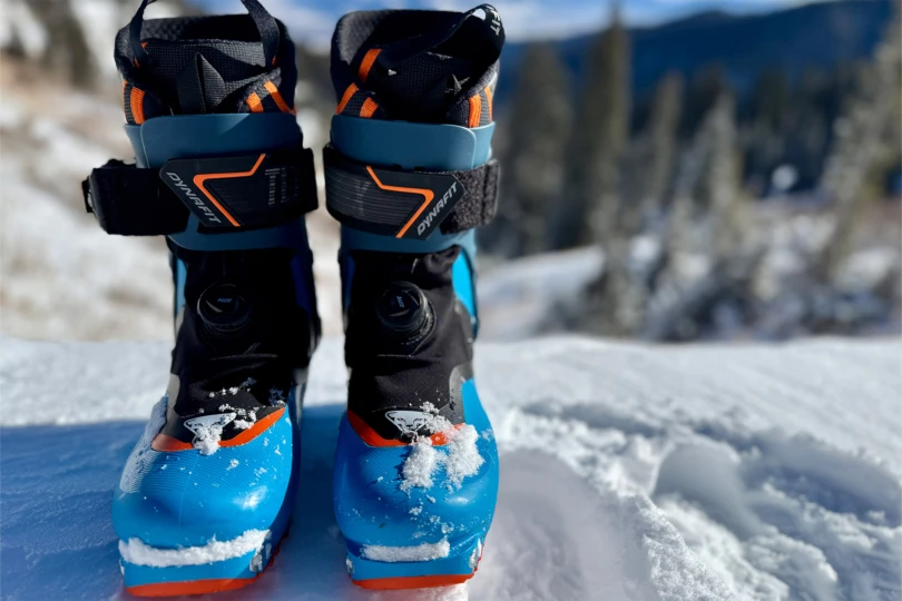 The boots are shown from the front with snow on the toes in bright light