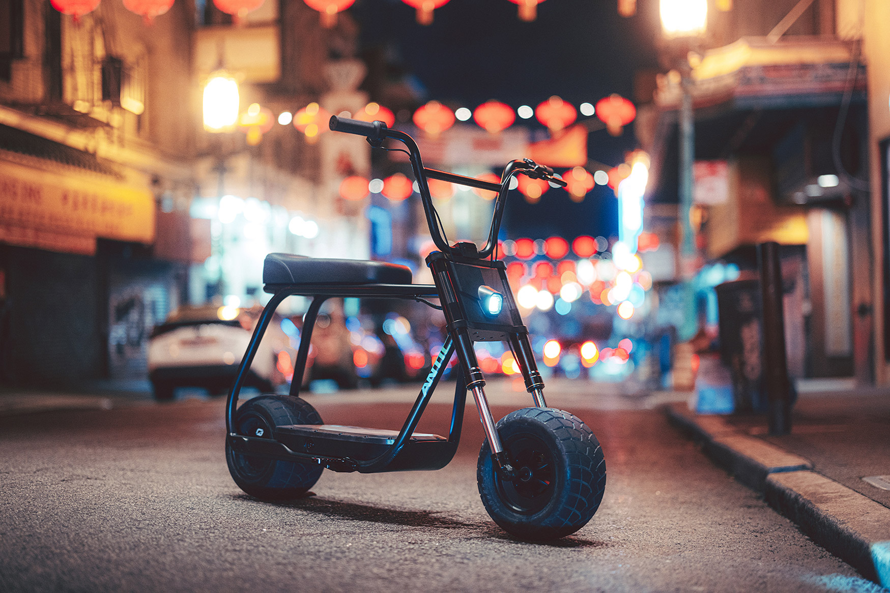 The Antic eBike stands alone on a city street at night with lights in the background