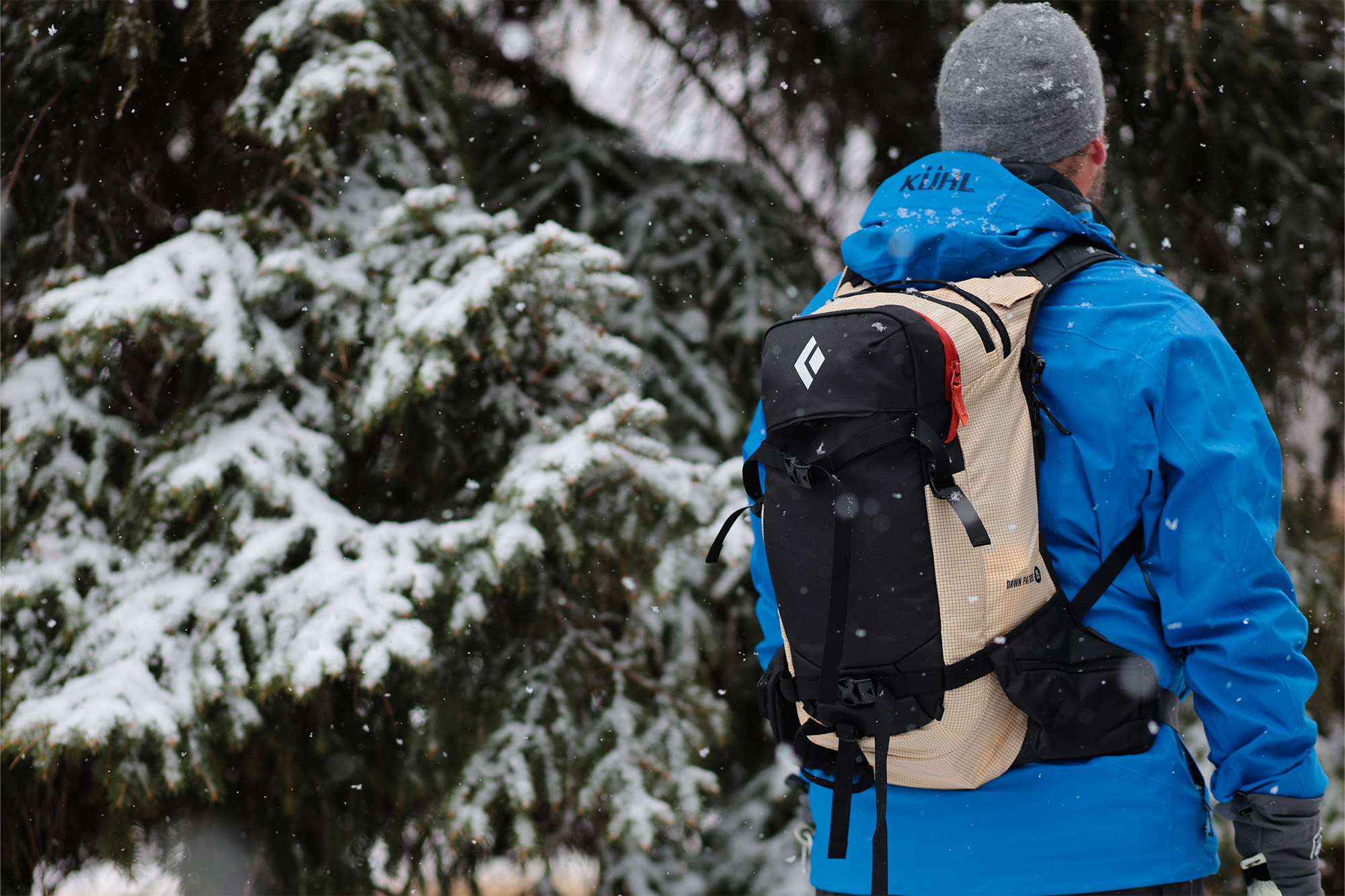A skier wearing the Black Diamond Dawn Patrol 25 Pack while standing in a snowy forest