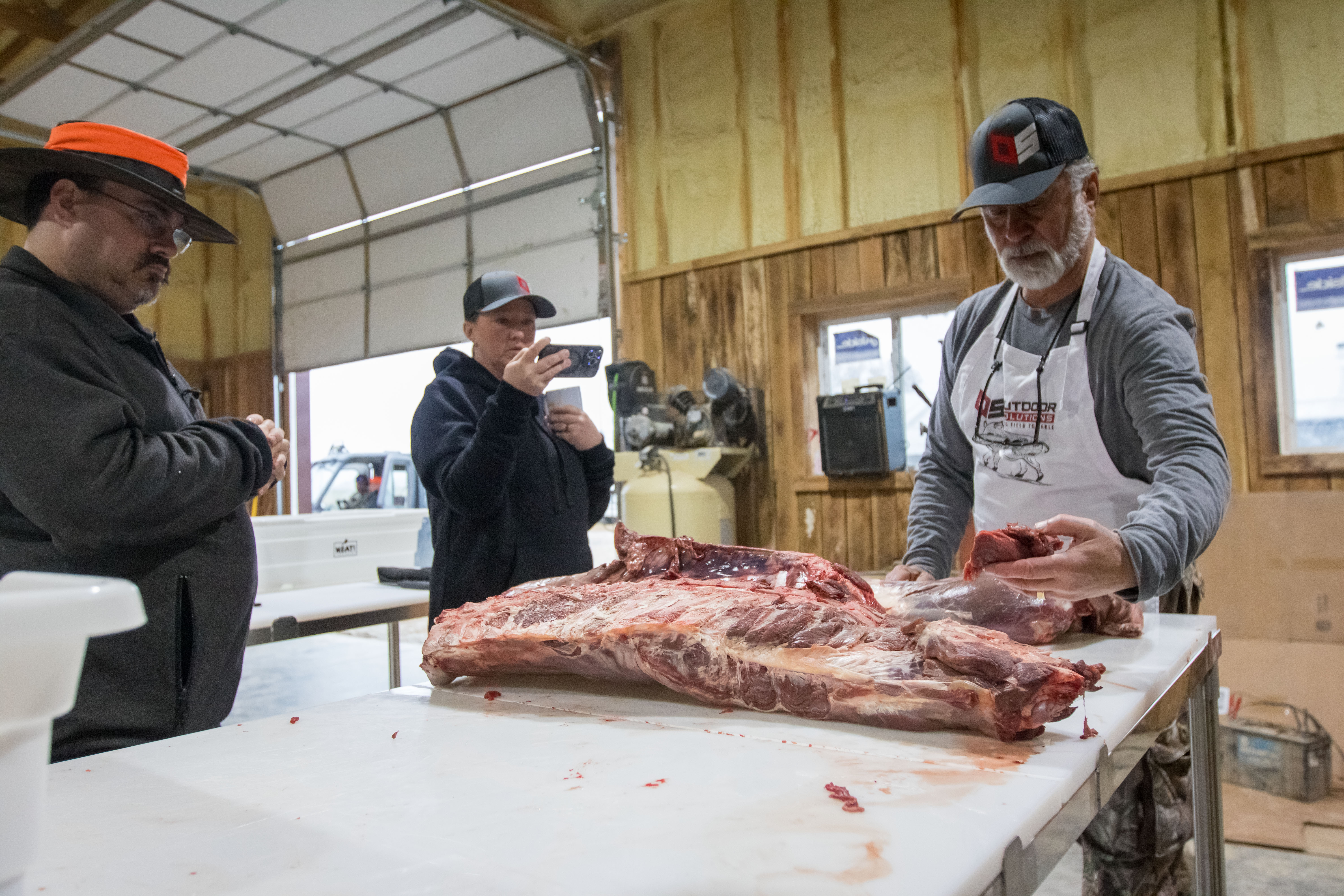 A chef instructing students how to butcher meat.