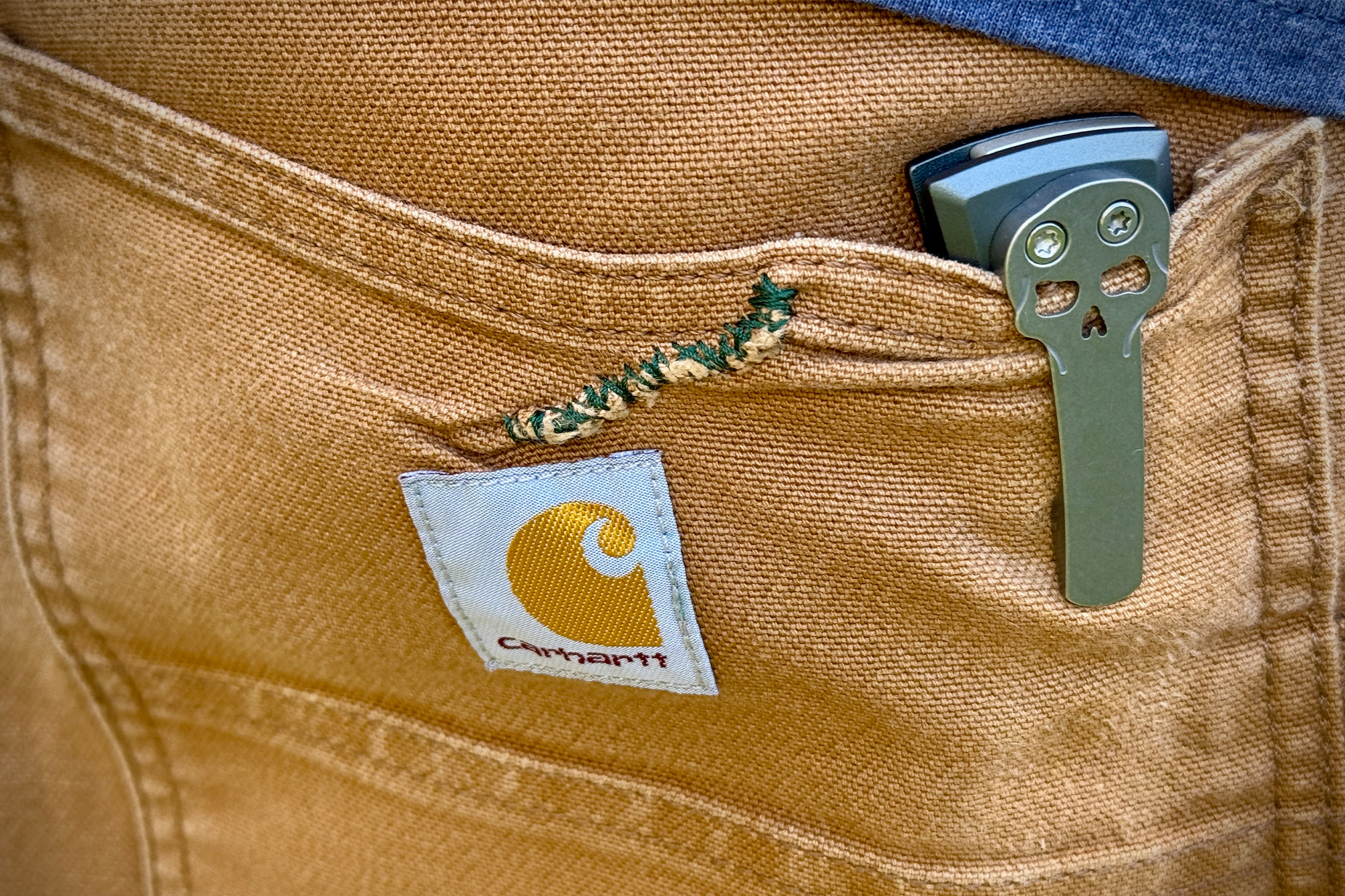 The knife clipped inside a pair of tan work pants, showing the skull pocket clip detail