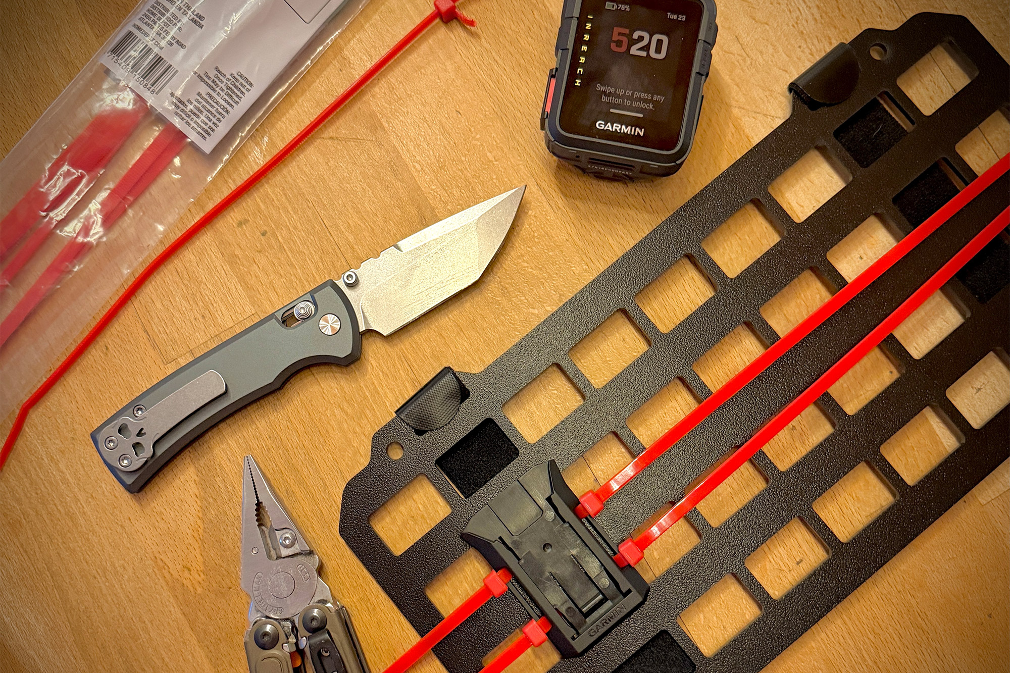 The folding knife placed on a table alongside everyday carry items, including a watch and multitool