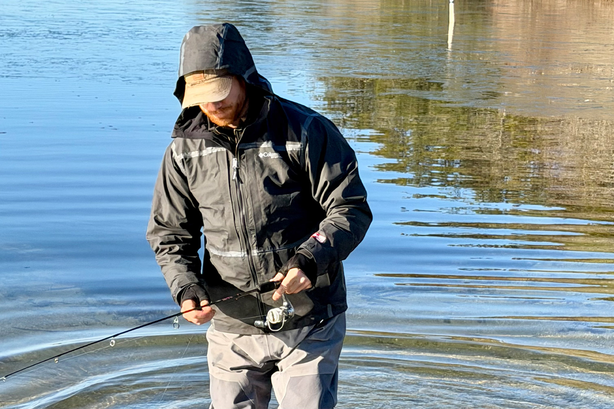A fisherman wearing the Columbia PFG Force XII™ ODX Jacket while fishing in calm, shallow water