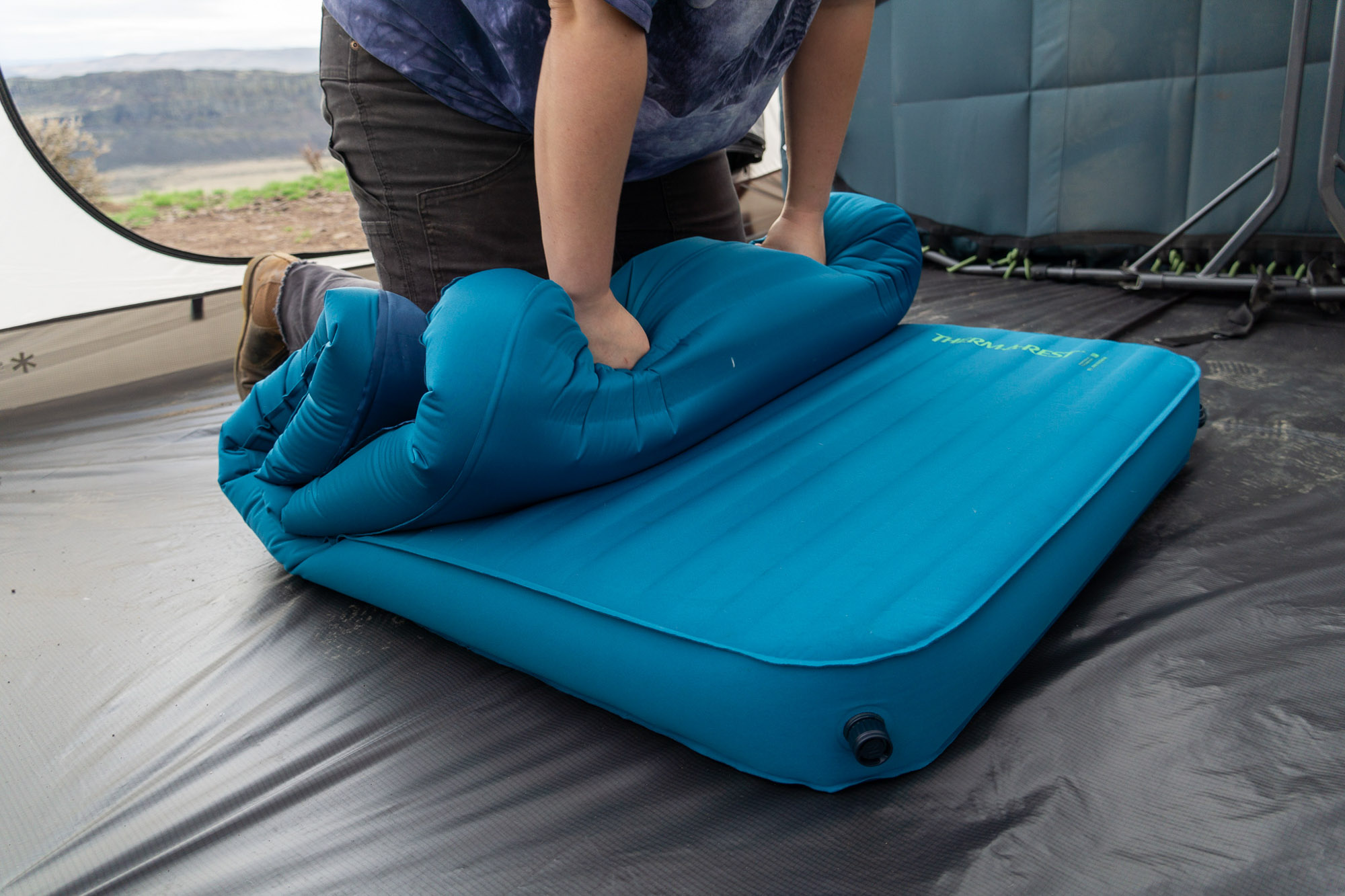 a camper leans on the therm-a-rest mondoking to get it to deflate totally before packing it